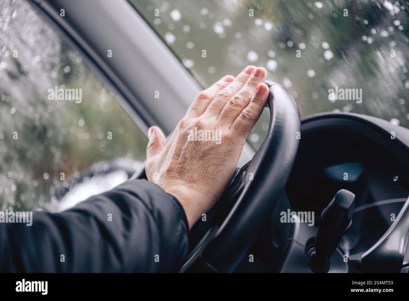 Hupendes Autohorn, männliche Hand am Autolenkrad an kalten Wintertagen, selektiver Fokus Stockfoto