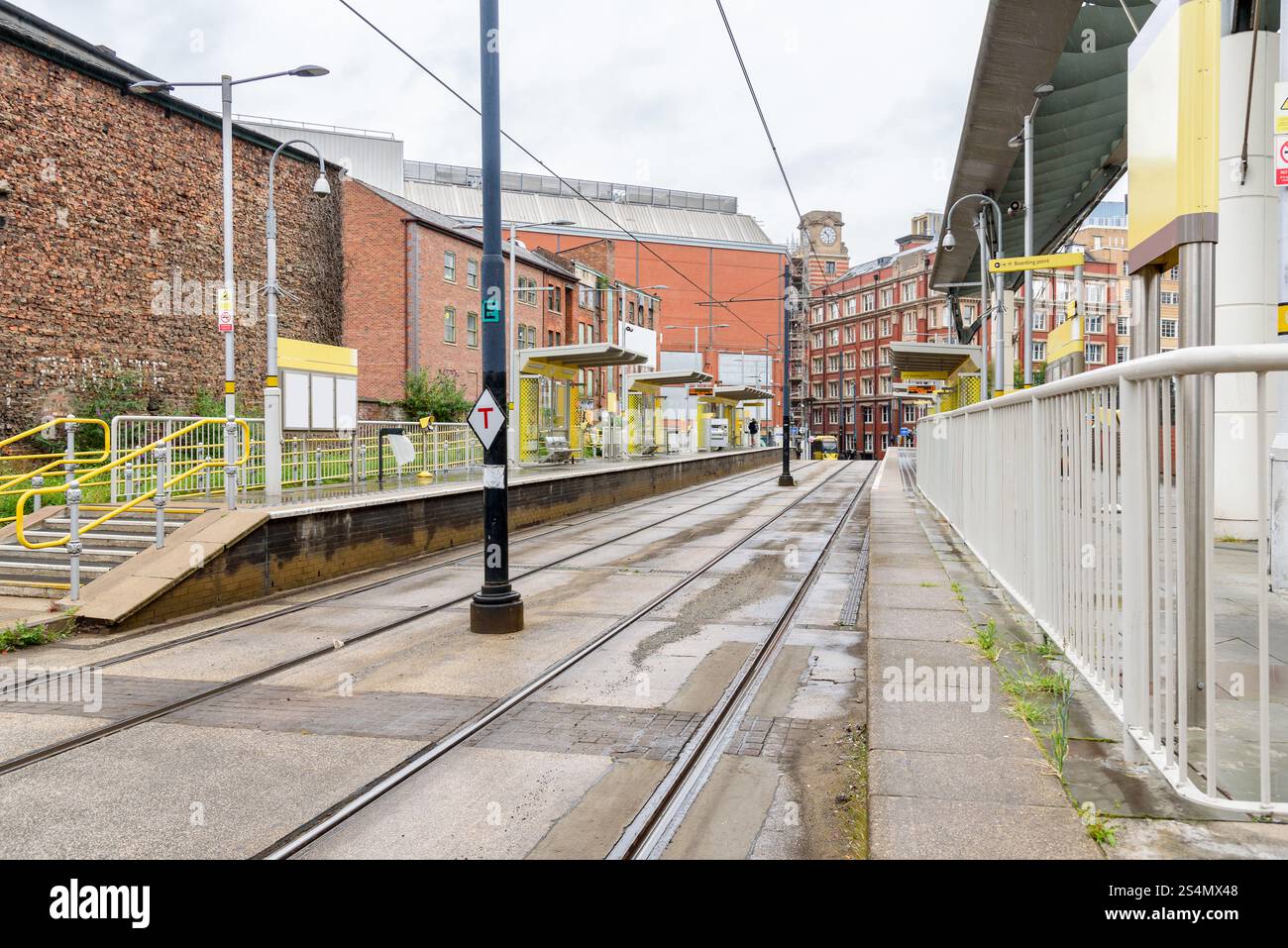 Verlassene Straßenbahnhaltestelle umgeben von traditionellen Backsteingebäuden in einem Stadtzentrum in England an einem Sommerregnetag Stockfoto