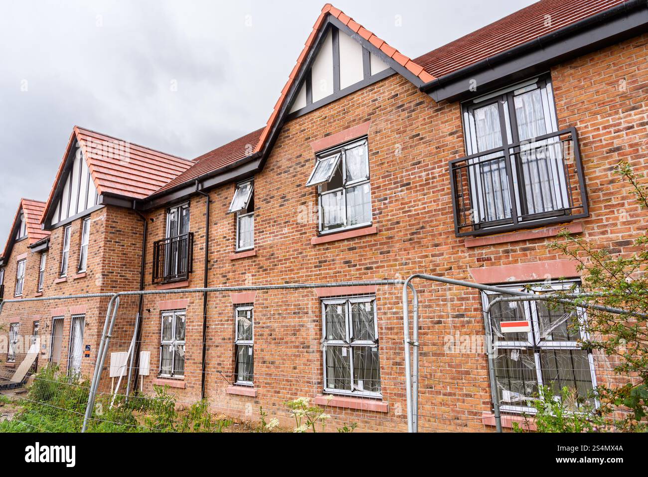 Ziegelterrassenhäuser im Bau in einer Wohnsiedlung auf dem Land Englands an einem Sommerregnetag Stockfoto