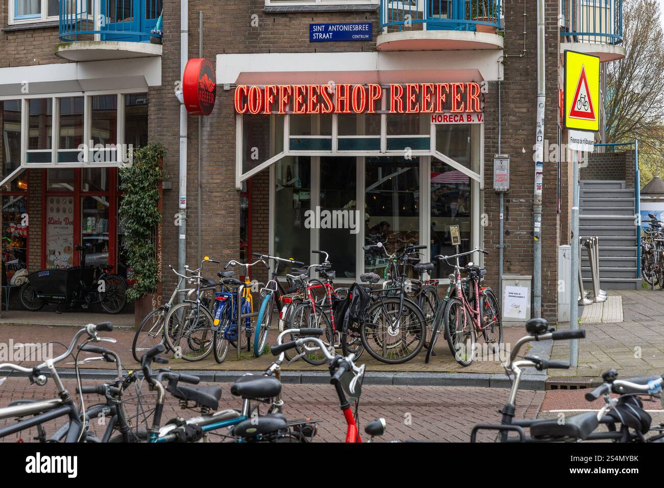 Amsterdam, Niederlande. 23. März 2024. Coffeeshop Reefer-Shop mit rotem Neon-Logo. Fahrräder vor dem Café. Stockfoto