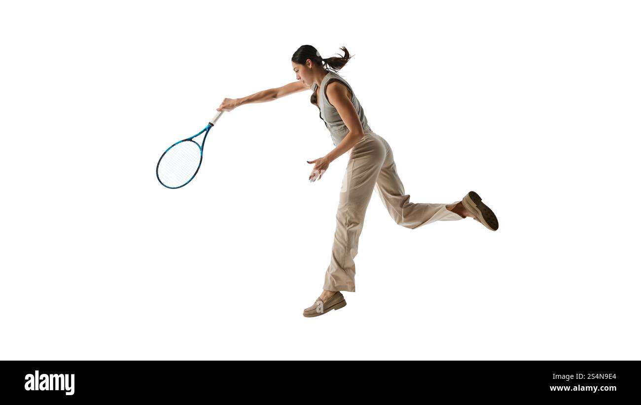 Frau, die mit Tennisschläger einen dynamischen Schwung ausführt, repräsentiert Meisterschaft und Engagement, um vor weißem Studiohintergrund Karriere zu machen. Stockfoto