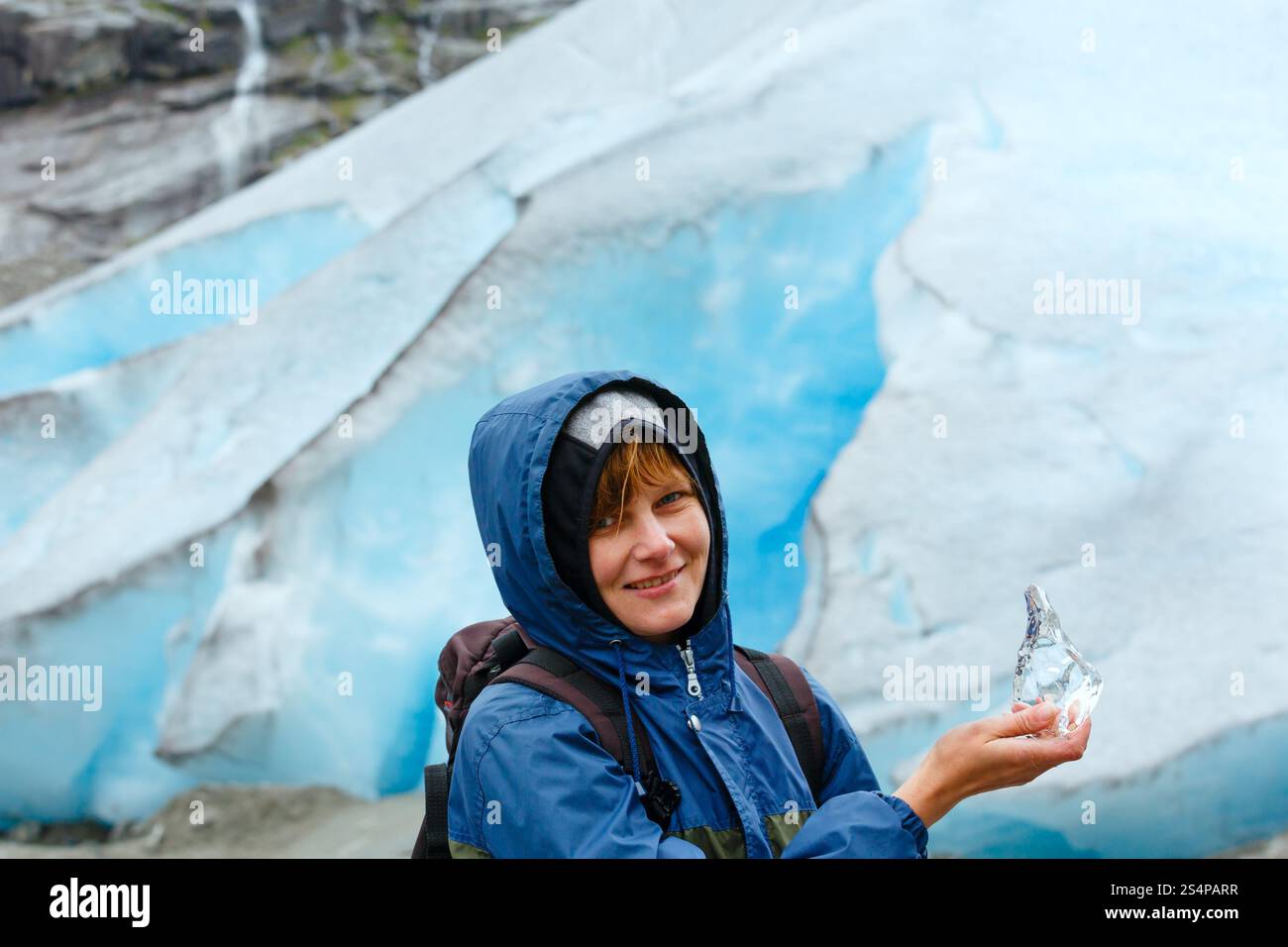 Glückliche Frau Porträt mit Stück Eis in der Hand am Nigardsbreen Gletscher Hintergrund (Norwegen) Stockfoto