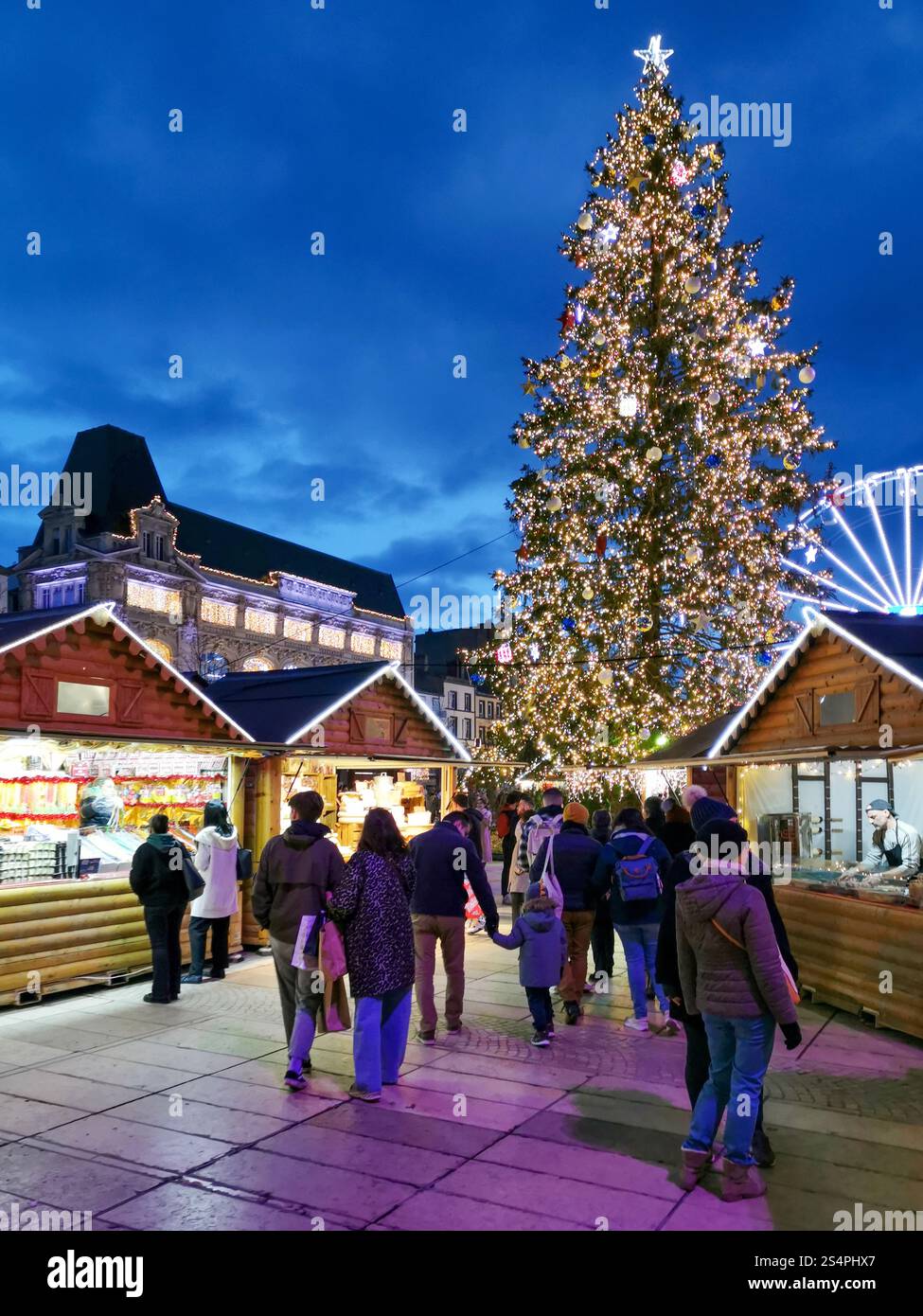 Besucher schlendern durch den Weihnachtsmarkt am Place de Jaude in Clermont-Ferrand und bewundern funkelnde Lichter und Weihnachtsdekorationen. Stockfoto