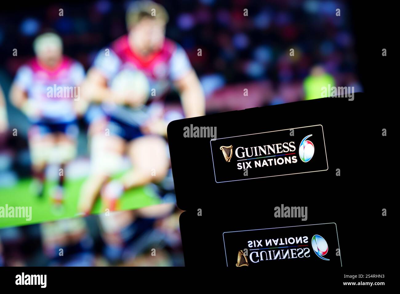 Ein Smartphone mit dem Logo der Guinness Six Nations Championship und einem unscharfen Rugby-Match im Hintergrund. Stockfoto
