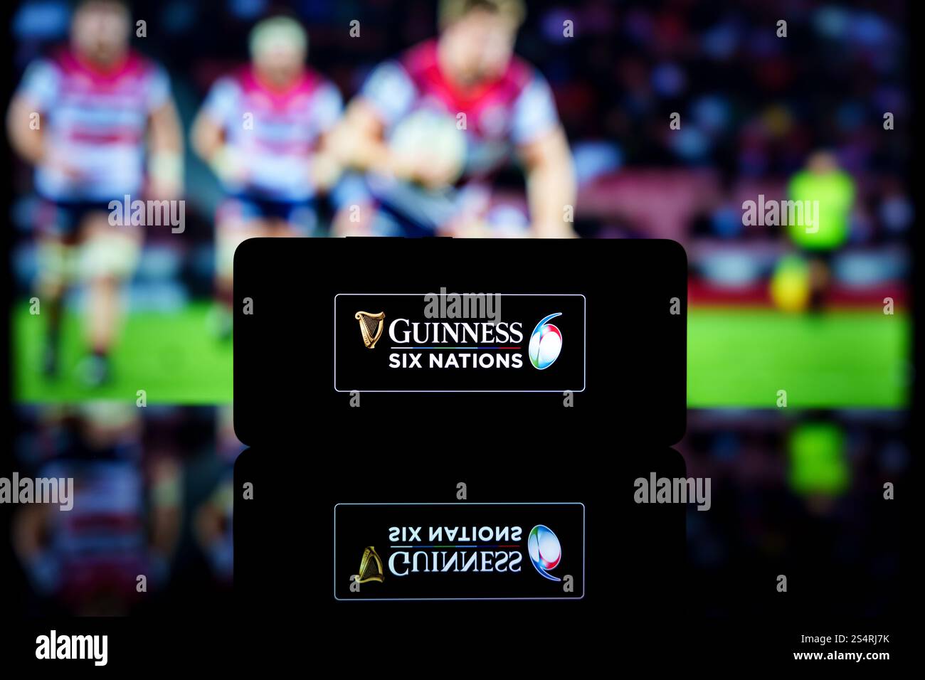 Ein Smartphone mit dem Logo der Guinness Six Nations Championship und einem unscharfen Rugby-Match im Hintergrund. Stockfoto