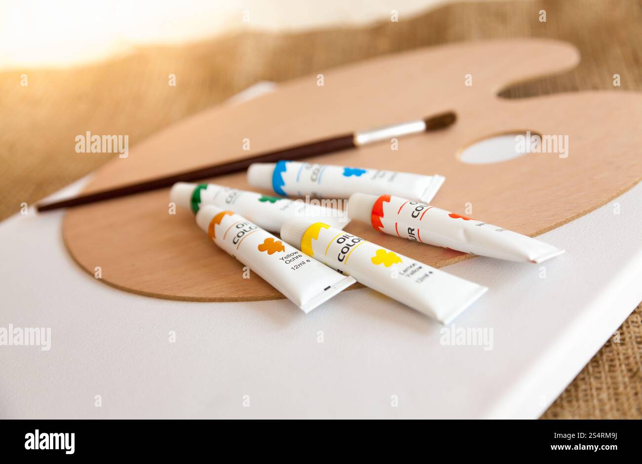 Bunte Ölfarben in Tuben und Pinsel auf Holzpalette liegend Stockfoto