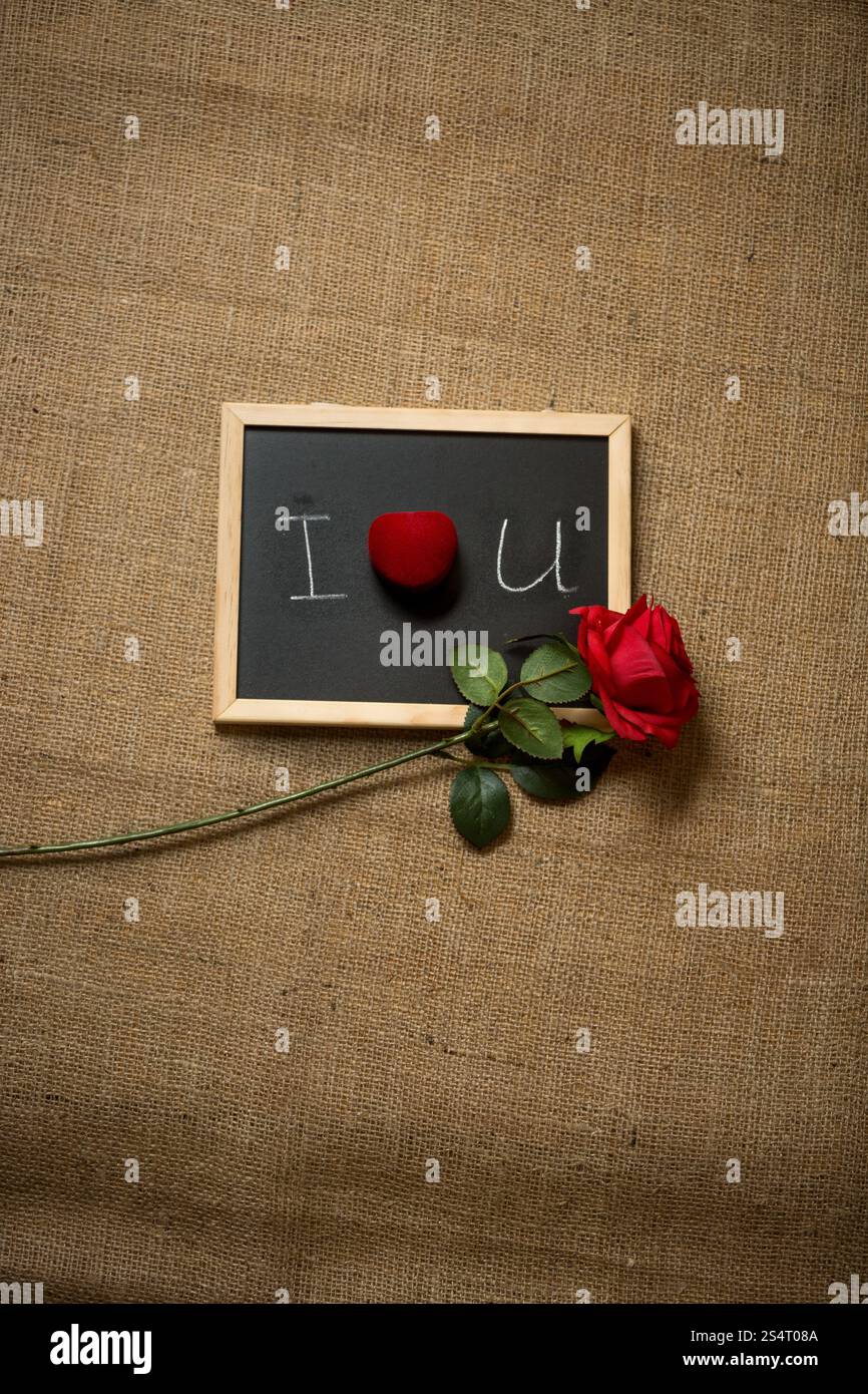 Rote Rose und Ehering liegend Liebeserklärung an Tafel geschrieben Stockfoto