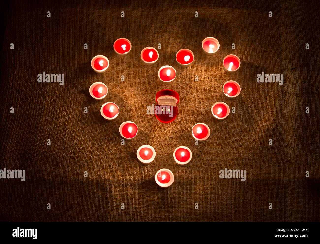 Nahaufnahme Foto goldenen Ring im Feld liegen in der Mitte der Herzform von Kerzen Stockfoto