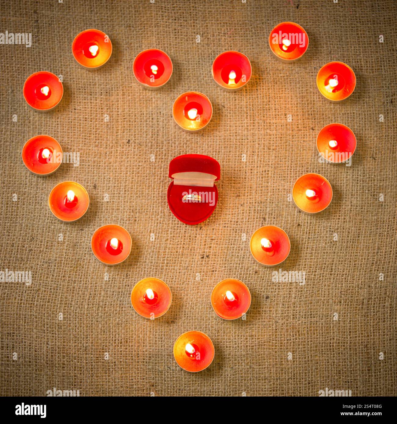 Closeup konzeptionelle Foto der Hochzeit Ring umgeben von Kerzen in Form von Herzen Stockfoto