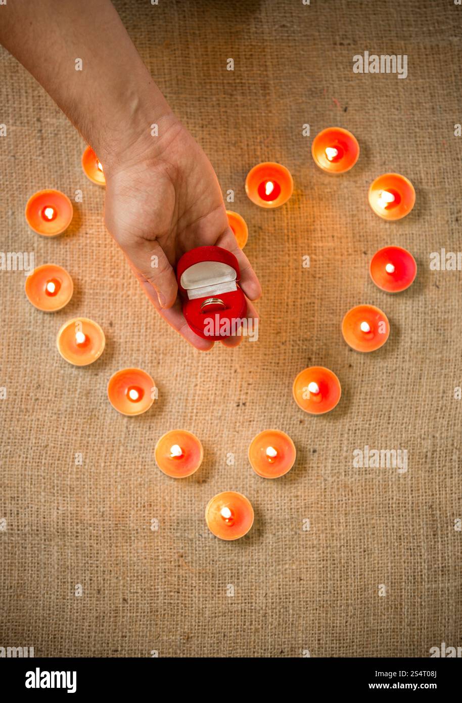 Konzeptionelle Foto Inhaber goldenen Ring im Feld gegen Herz Kerzen Stockfoto