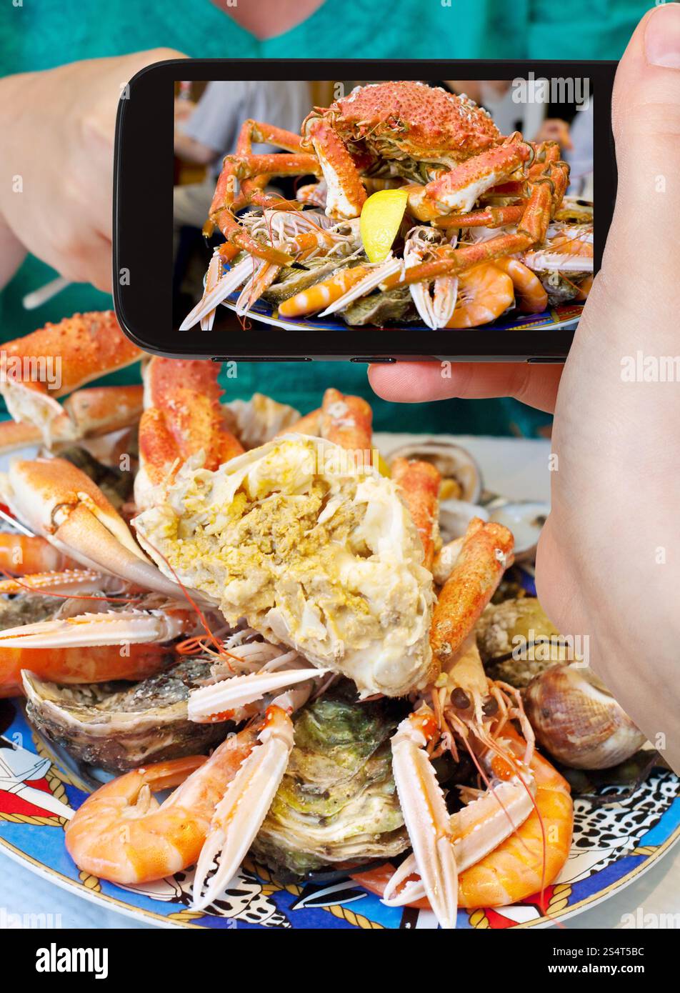 Fotografieren Food-Konzept - Tourist nimmt Bild der Meeresfrüchte-Platte mit Krabben, Garnelen, Garnelen auf Smartphone, Frankreich Stockfoto
