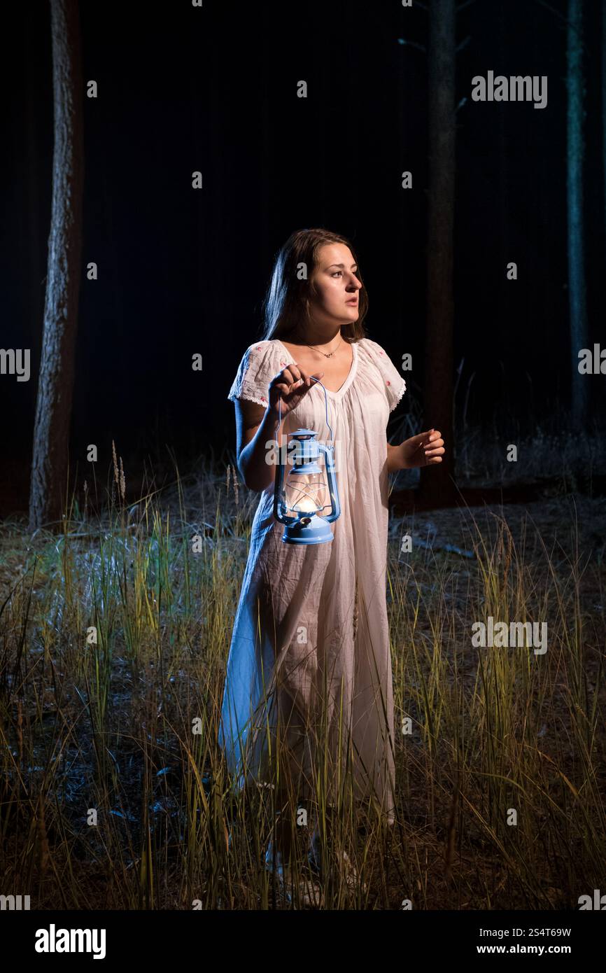 Einsame verlorene Frau im Wald in der Nacht zu Fuß mit Kerze Laterne Stockfoto