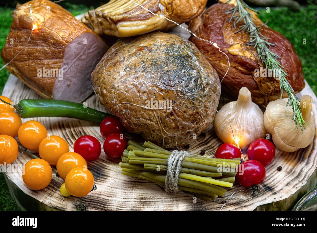 Verschiedene Schinken und Wurstwaren auf Platte umgeben von Gemüse. Design Metzgerei Schaufenster Display. Stockfoto