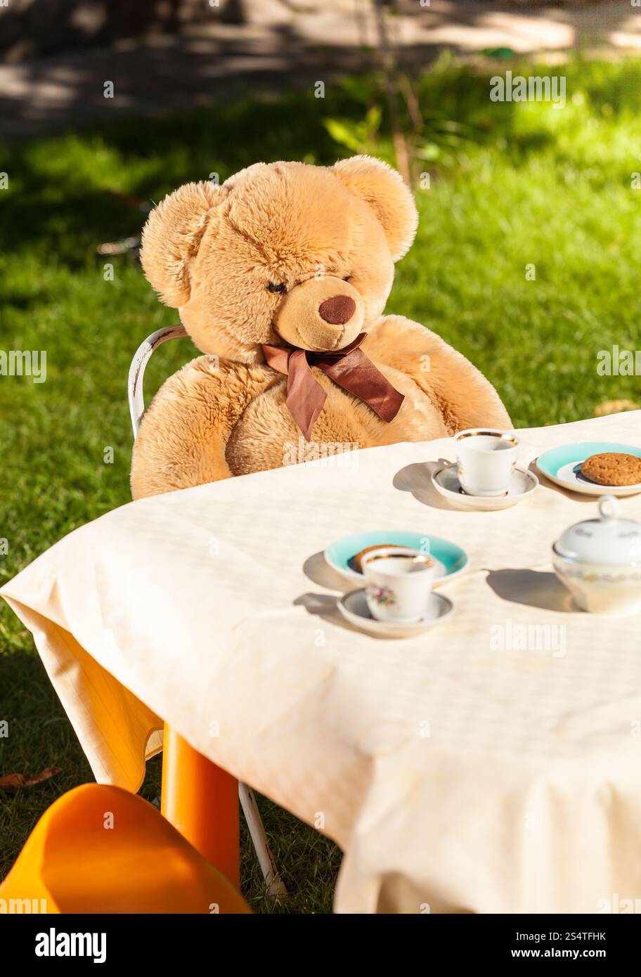 Großer Teddybär hinter Tisch zu sitzen und Tee trinken Stockfoto
