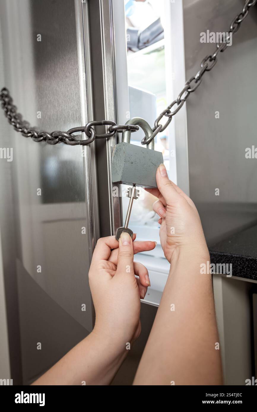 Junge Frau, die Sperre für Kühlschrank mit großer Schlüssel öffnen Stockfoto Junge Frau, die Sperre für Kühlschrank mit großer Schlüssel öffnen Stockfoto