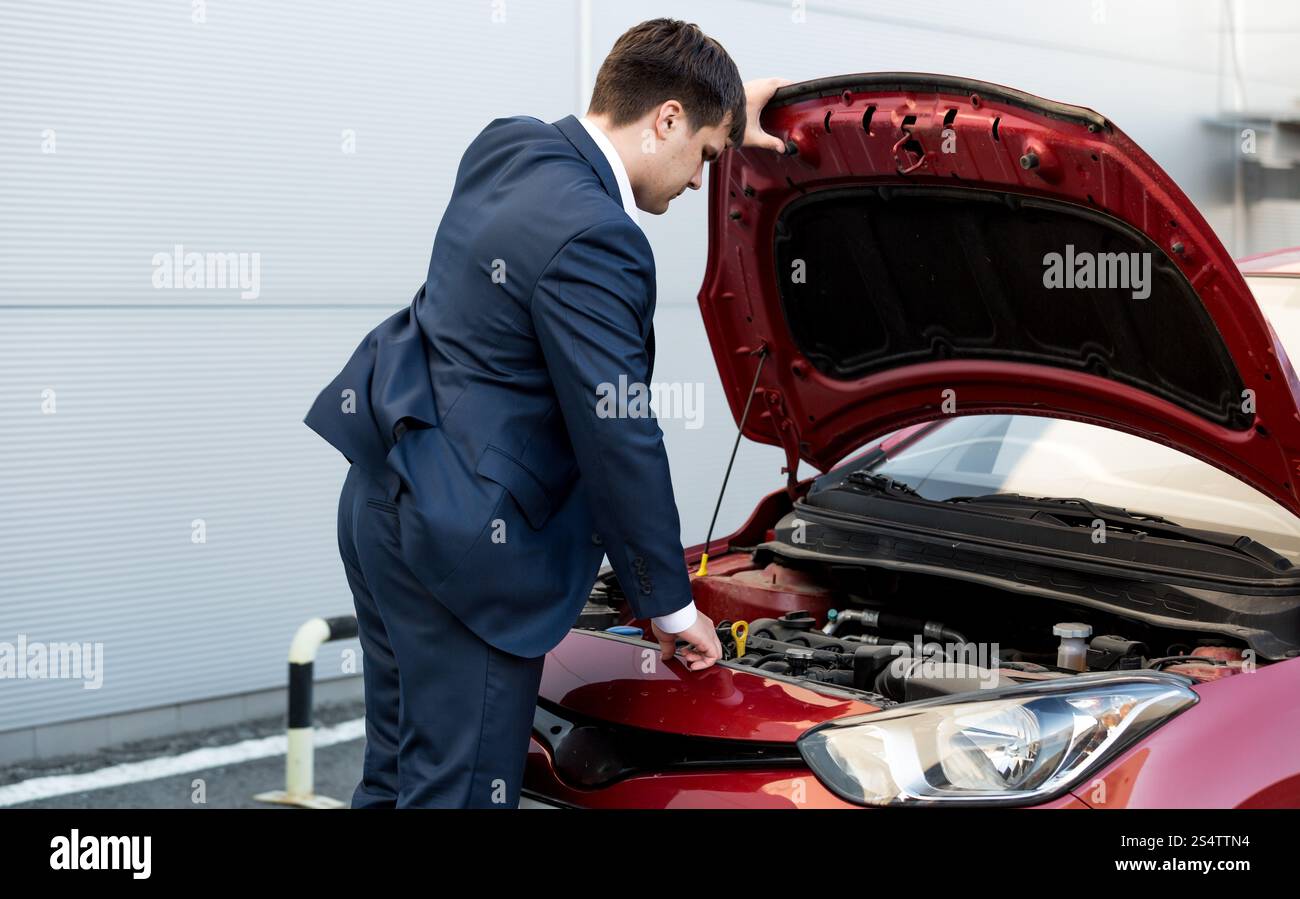 Junger Geschäftsmann im Anzug, die Öffnung der Motorhaube des offenen Wagen Stockfoto