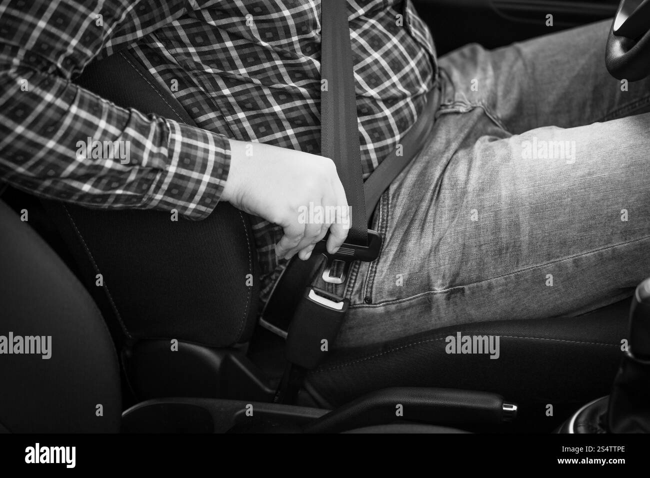 Black And White Nahaufnahme Foto des Mannes Befestigung Sicherheitsgurt im Auto Stockfoto