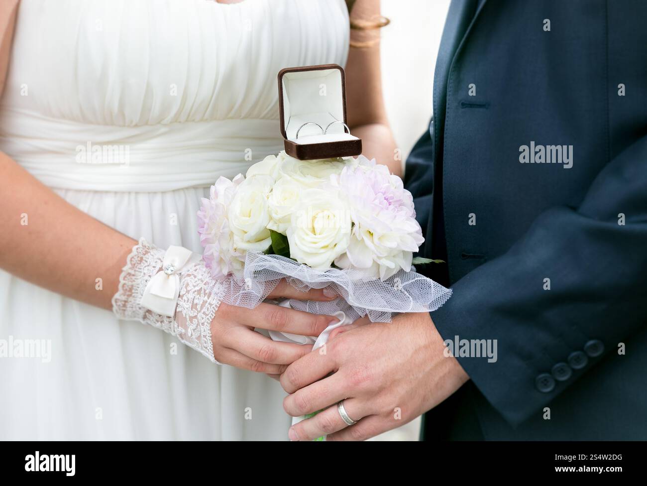 Nahaufnahme von Braut und Bräutigam, die einen Hochzeitsstrauß mit goldenen Ringen halten Stockfoto