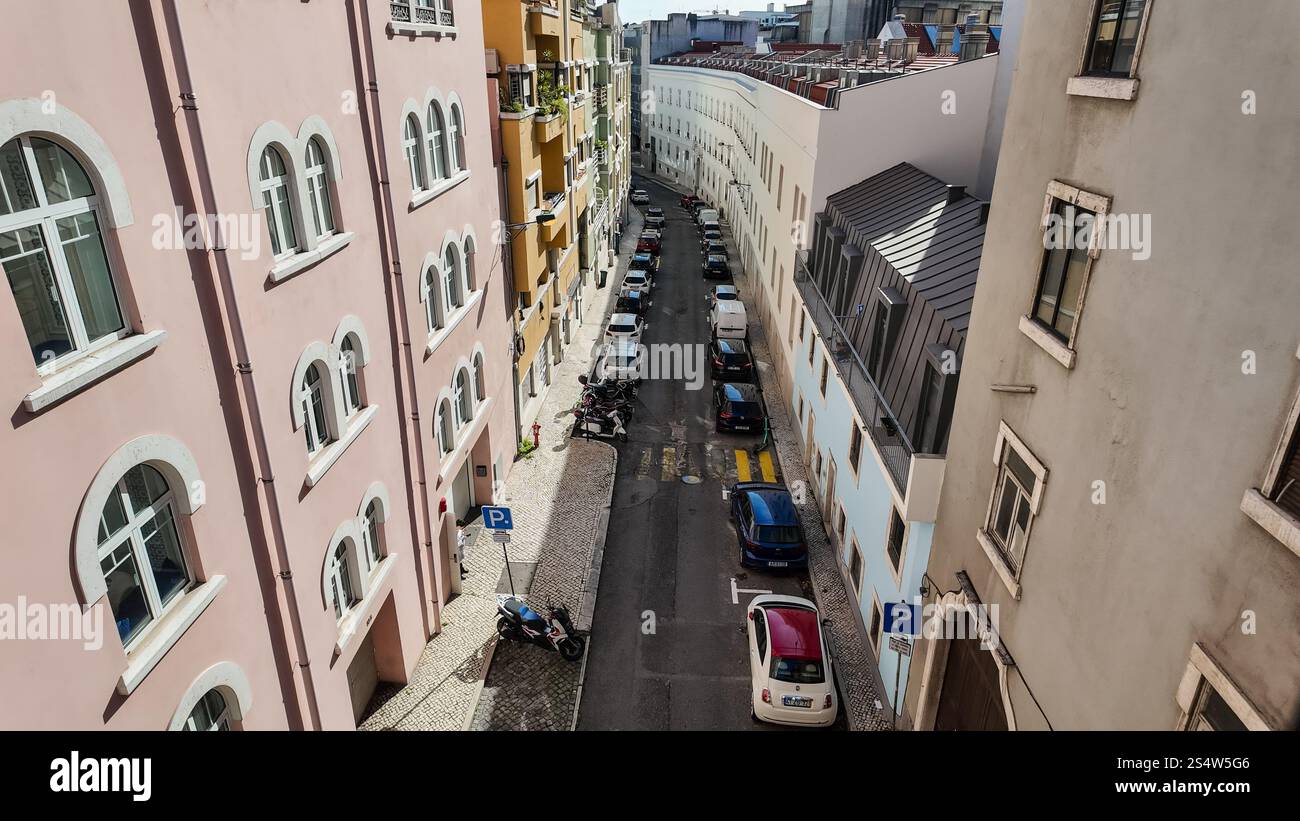Ein Blick von oben, mit Blick auf eine enge Straße in Lissabon mit Autos auf beiden Seiten und Gebäuden entlang der Straße. Stockfoto