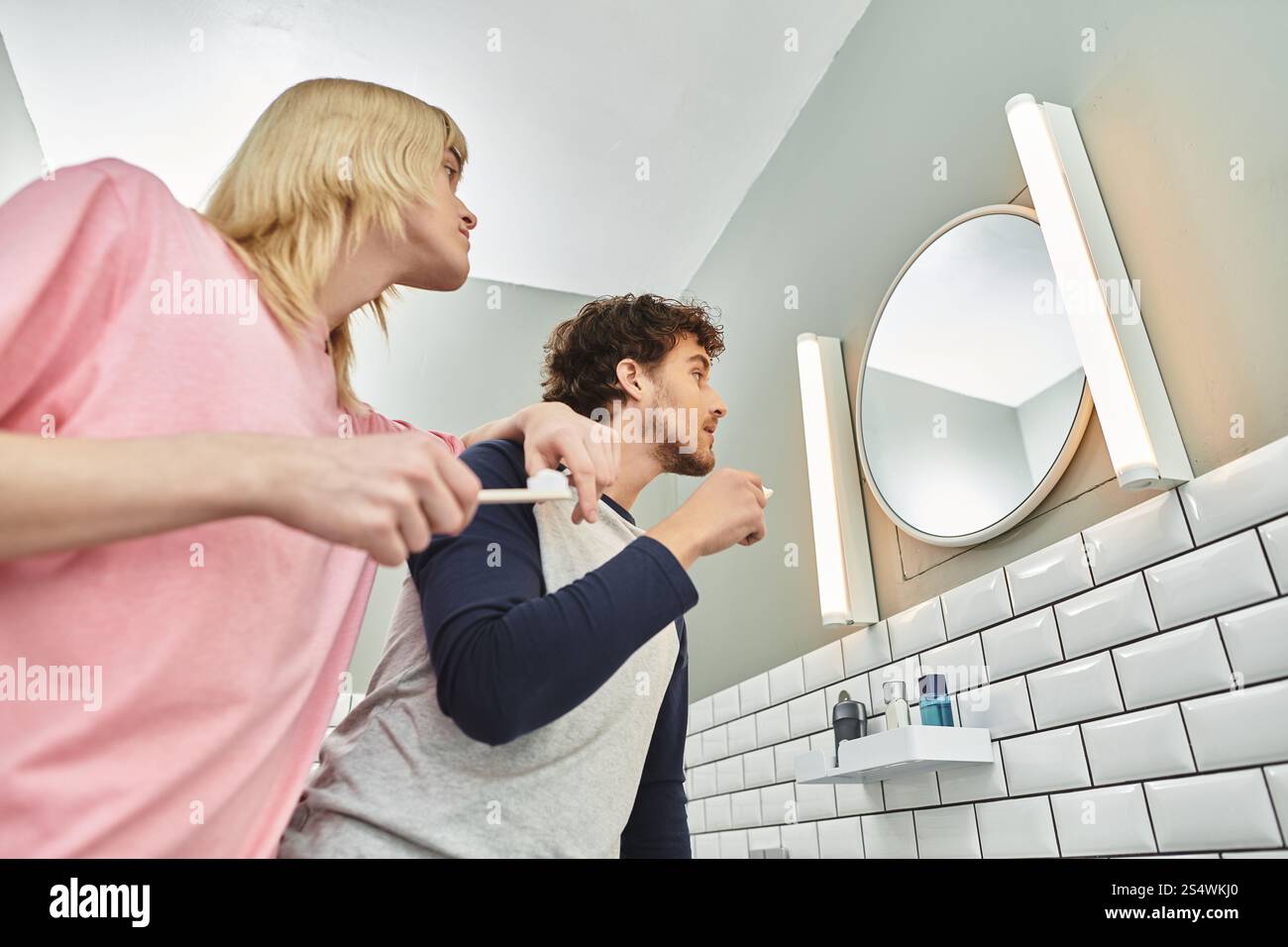 In einem fröhlichen Badezimmer genießen zwei Männer eine Morgenroutine, gemeinsam Lächeln und Lachen. Stockfoto