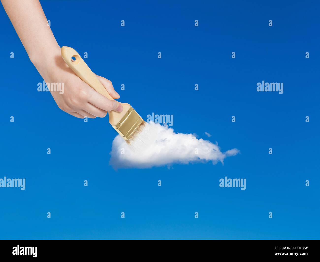 Wetter-Konzept - Hand mit Pinsel malt einsame weiße Wolke am blauen Himmel im blauen Sommerhimmel Stockfoto