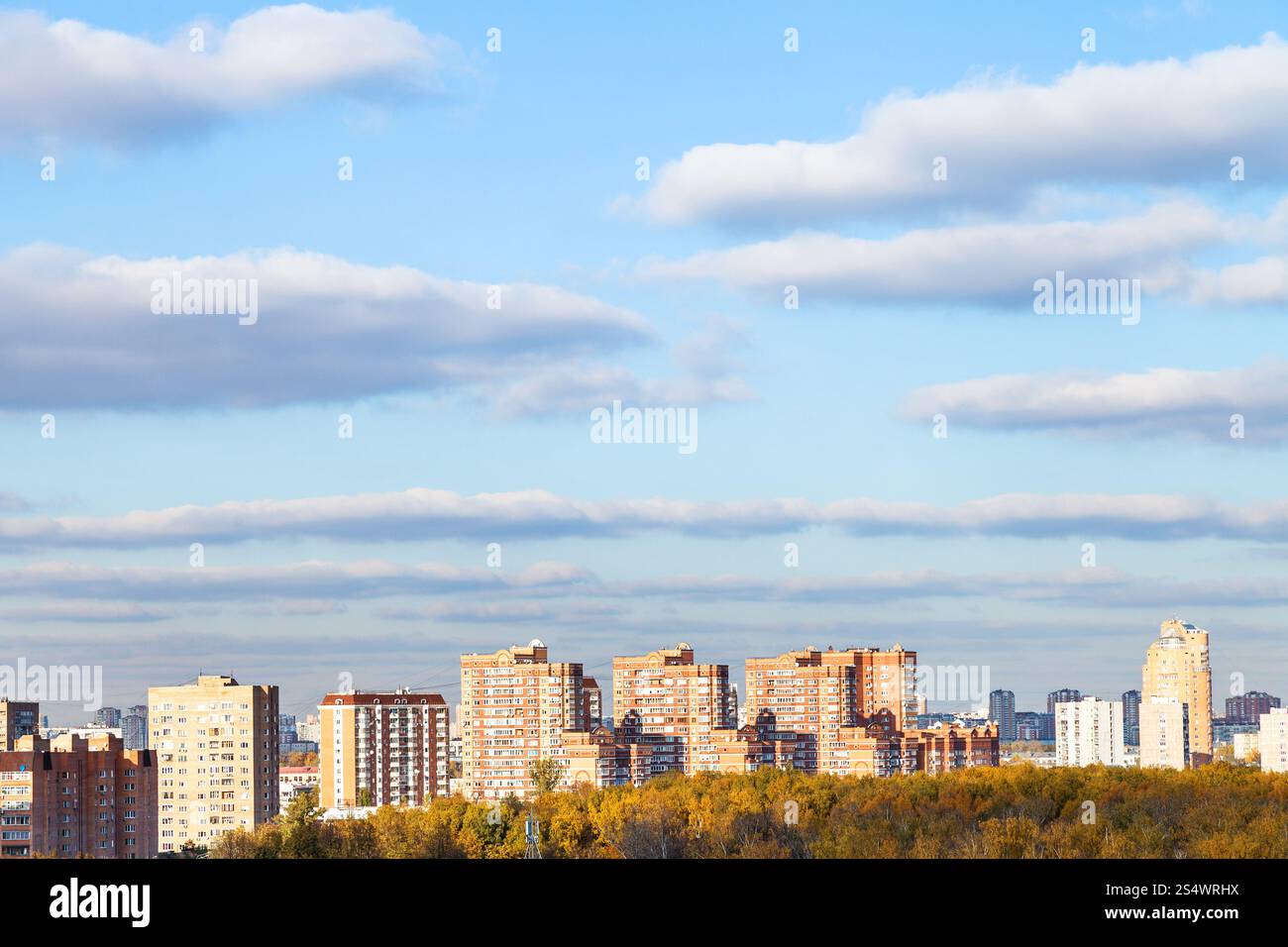 blauer Himmel mit Wolken über moderne Apartmenthäuser und gelbe Wälder in sonnigen Herbsttag Stockfoto