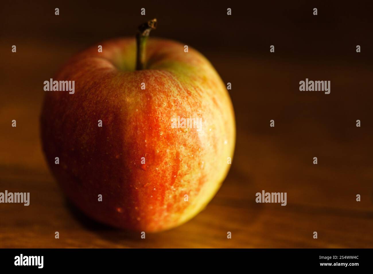 reifer Apfel auf Holztisch mit Abendsonne beleuchtet Stockfoto