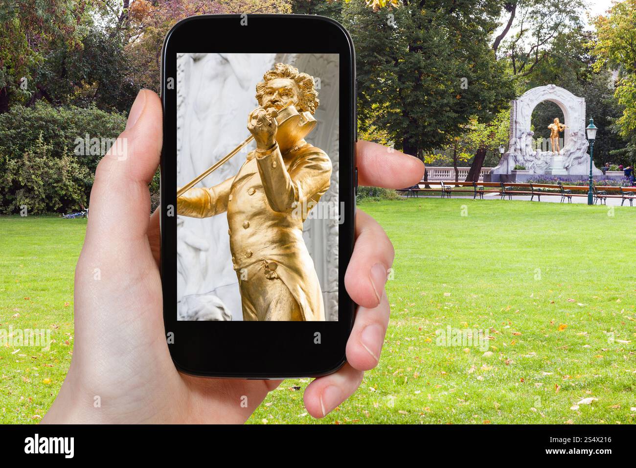 Travel Concept - touristische Snapshot aus vergoldeter Bronze staue der Walzerkönig Johann Strauss Sohn im Stadtpark (City Park) in Wien auf dem Smartphone Stockfoto