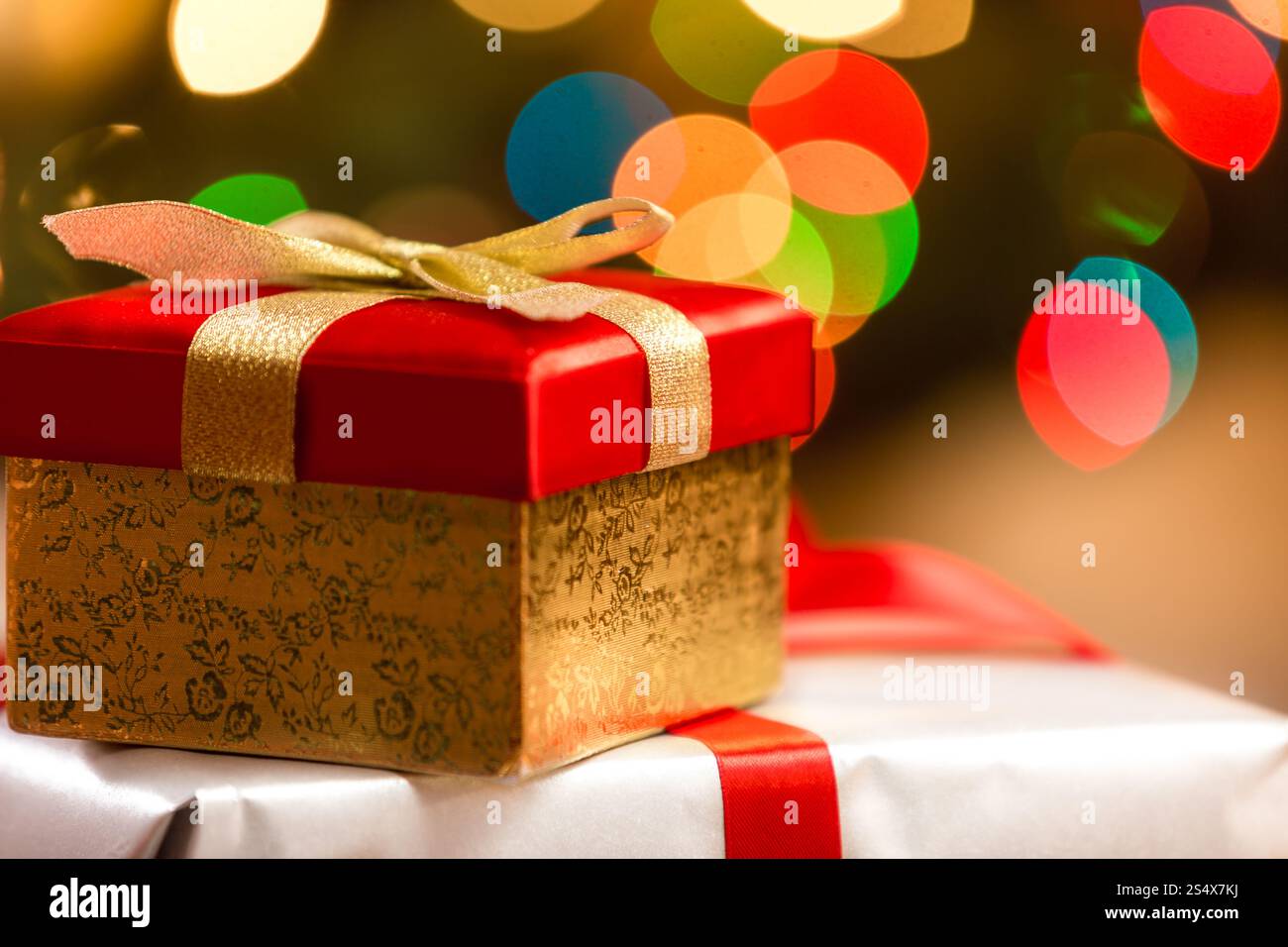 Red Christmas Box mit goldenen Band auf Grund von bunten Lichtern Stockfoto