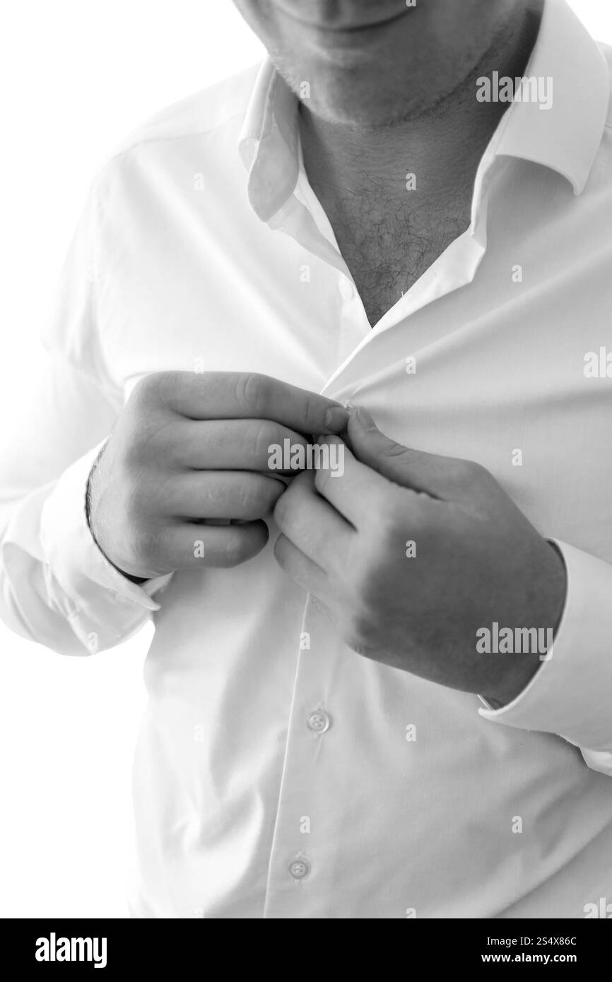 Schwarzweißfoto eines jungen Mannes, der ein weißes Hemd anzieht Stockfoto