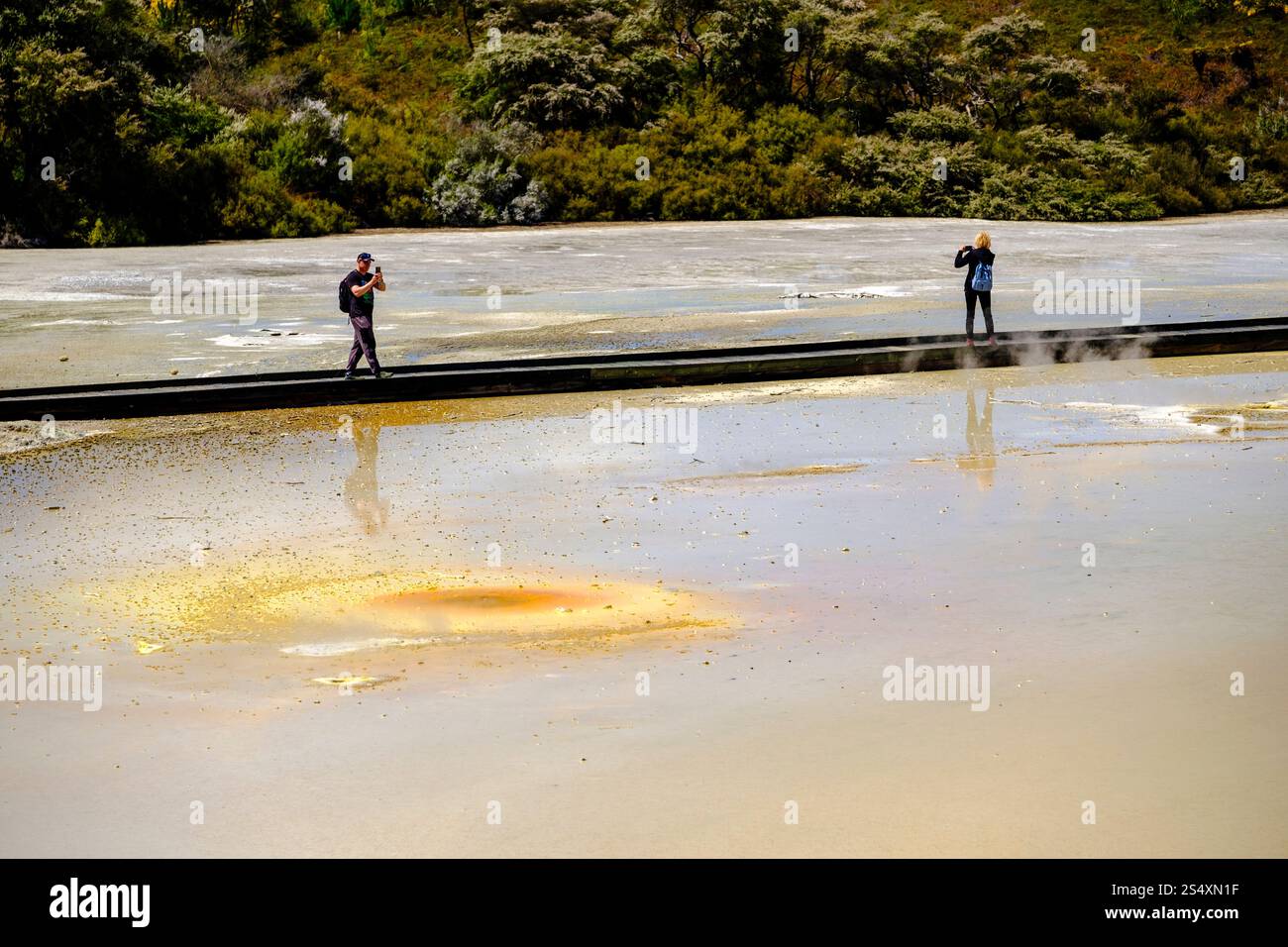 Besucher gehen auf der Promenade durch den Champagne Pool im Wai-O-Tapu Thermal Wonderland, Rotorua, Neuseeland, Neuseeland, und erkunden farbenfrohe geothermische Pools. Stockfoto