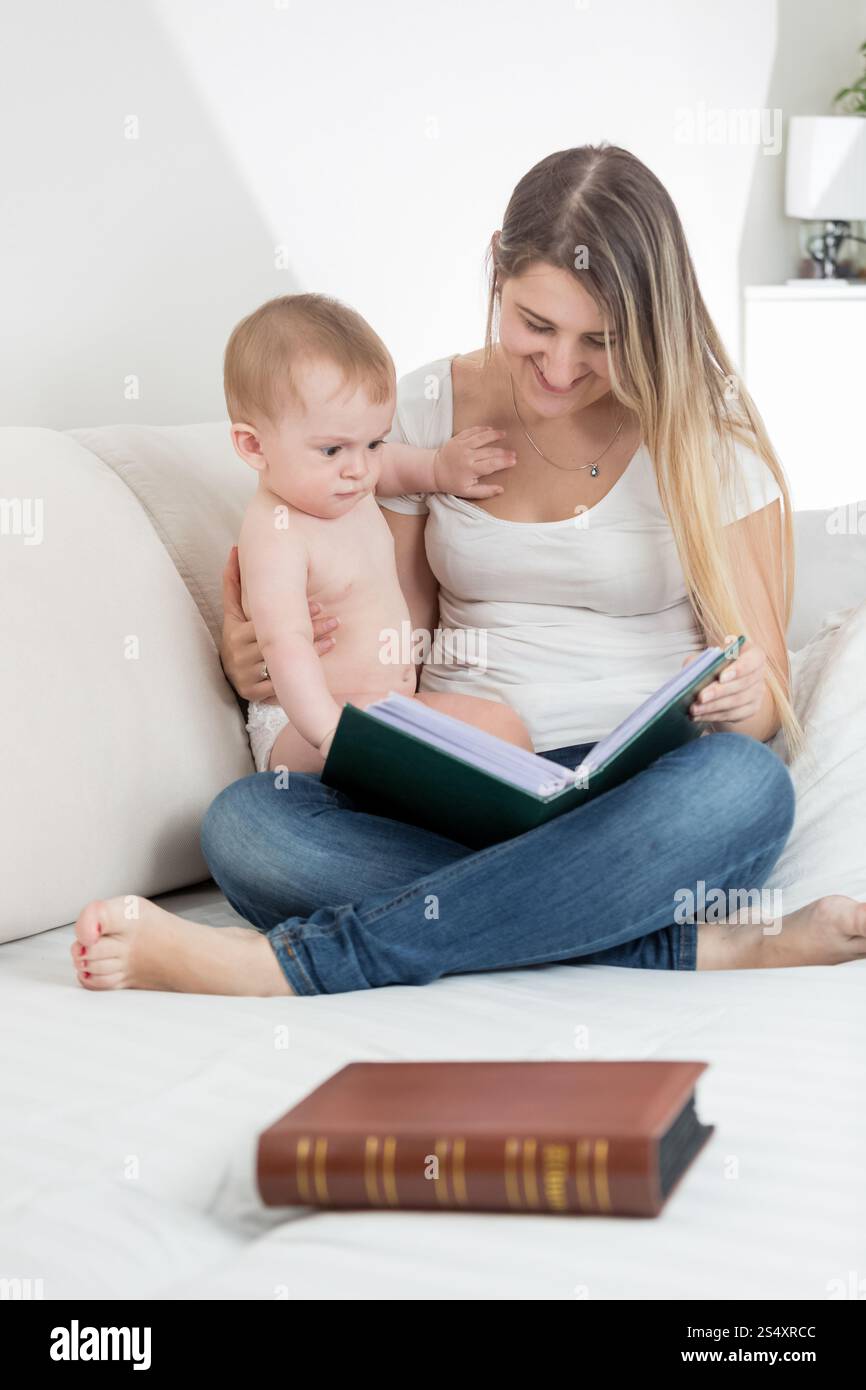 Schöne lächelnde Mutter zeigt Bilder in alten Buch ihr 9 Monate altes Baby boy Stockfoto