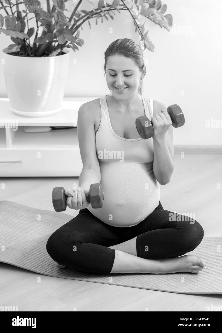 Schwarz / weiß Foto schwangere Frau das Training mit Hanteln zu Hause Stockfoto