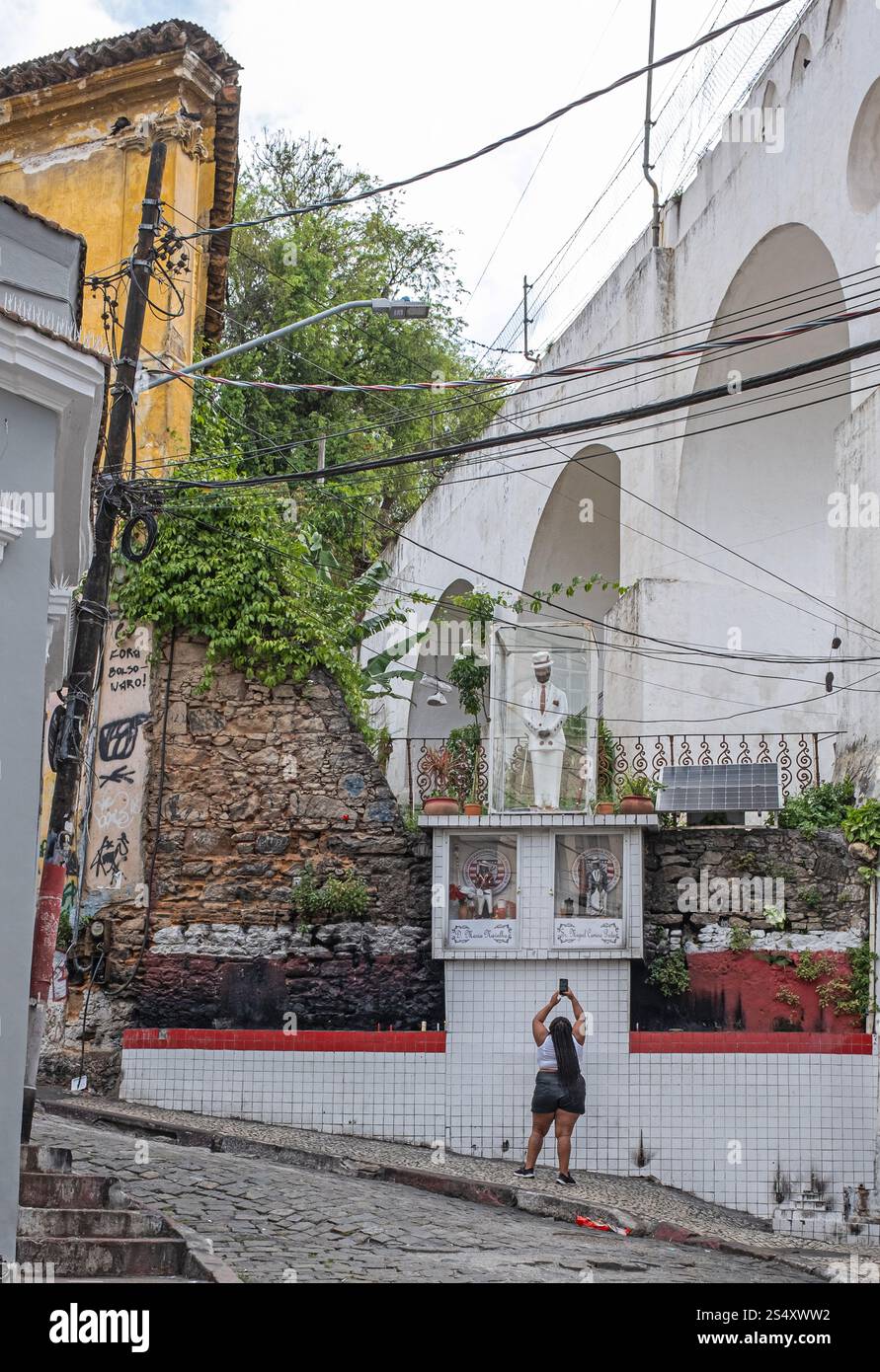 Eine Frau macht ein Foto von der Statue von Ze Pelintra, vor dem gleichnamigen Heiligtum im Lapa-Viertel von Rio de Janeiro, Brasilien. Stockfoto