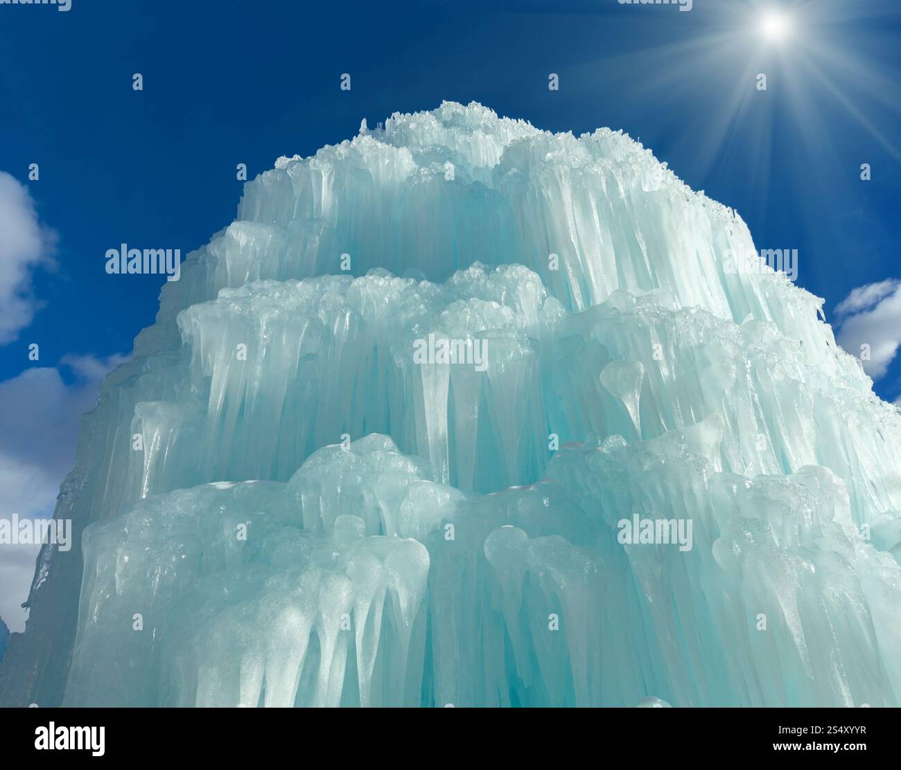 Gefrorenes Wasser in Brunnen (Eiswasserfall) auf sonnenglänzendem Himmel Hintergrund. Stockfoto