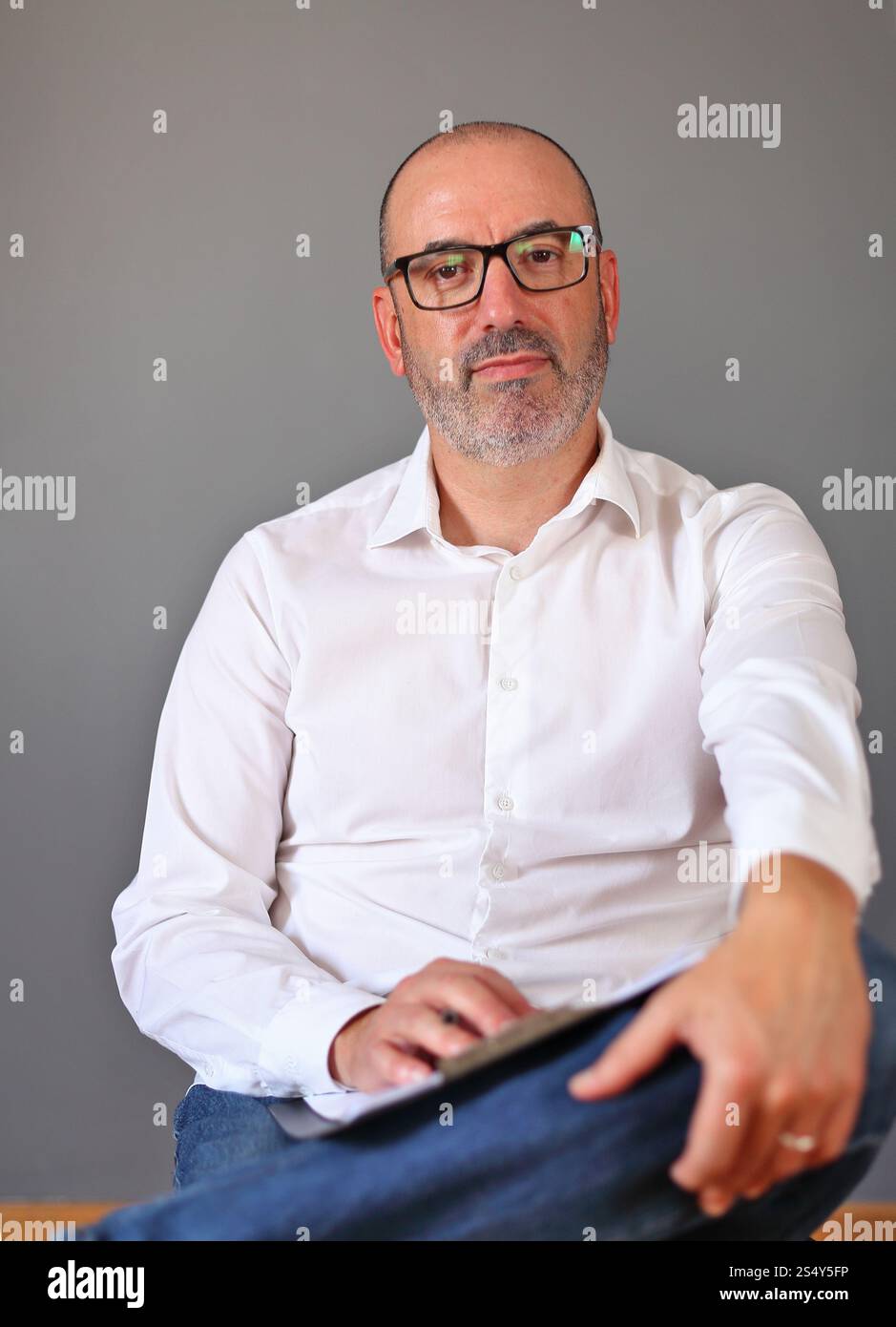 Eine reife Person in einer entspannten Position, die bei der Prüfung von Dokumenten in legeren Geschäftskleidung trägt. Das Bild spiegelt Professionalität, Selbstvertrauen, A wider Stockfoto