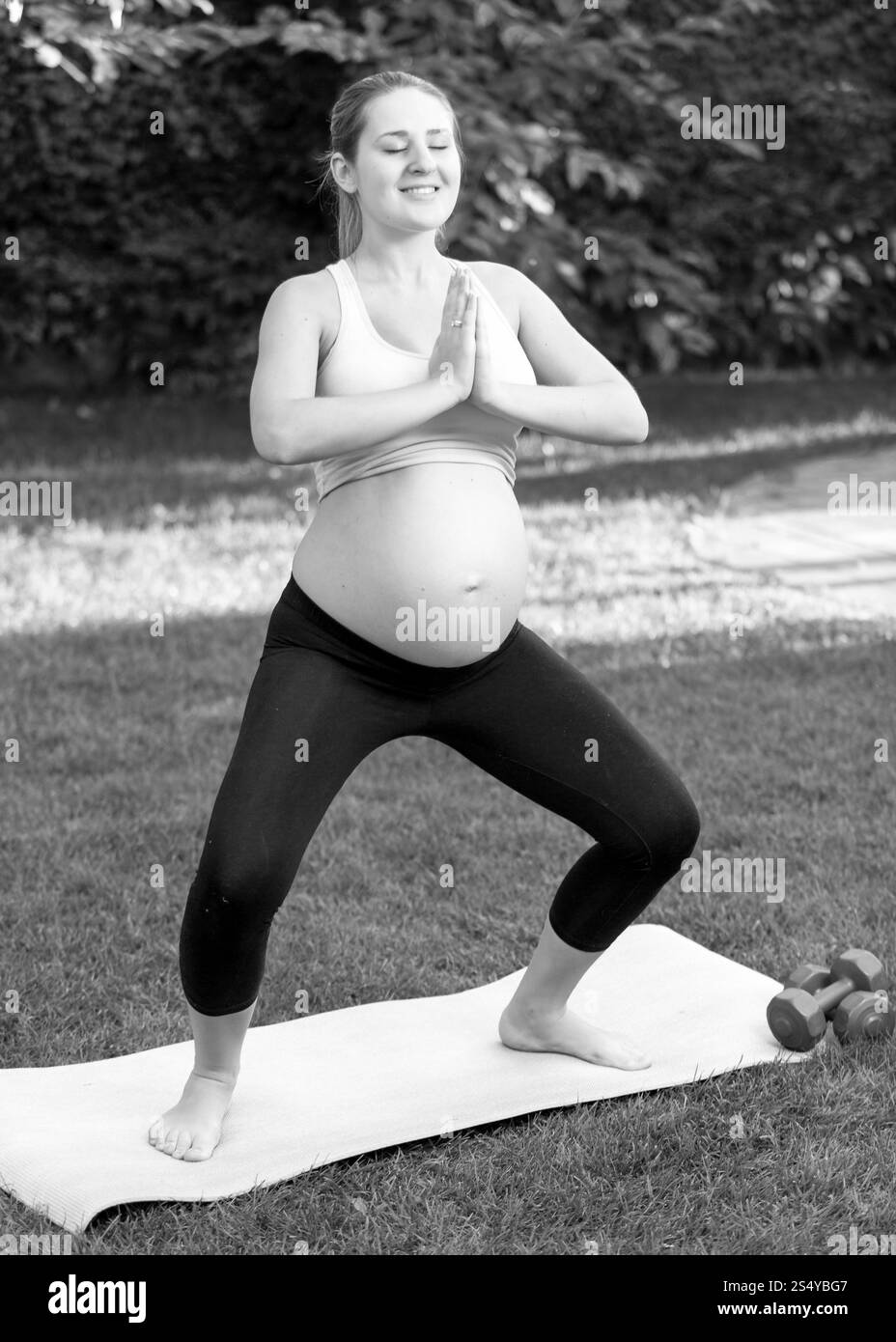 Schwarz-weiß-Aufnahme einer schwangeren Frau, die Yoga im Park praktiziert Stockfoto