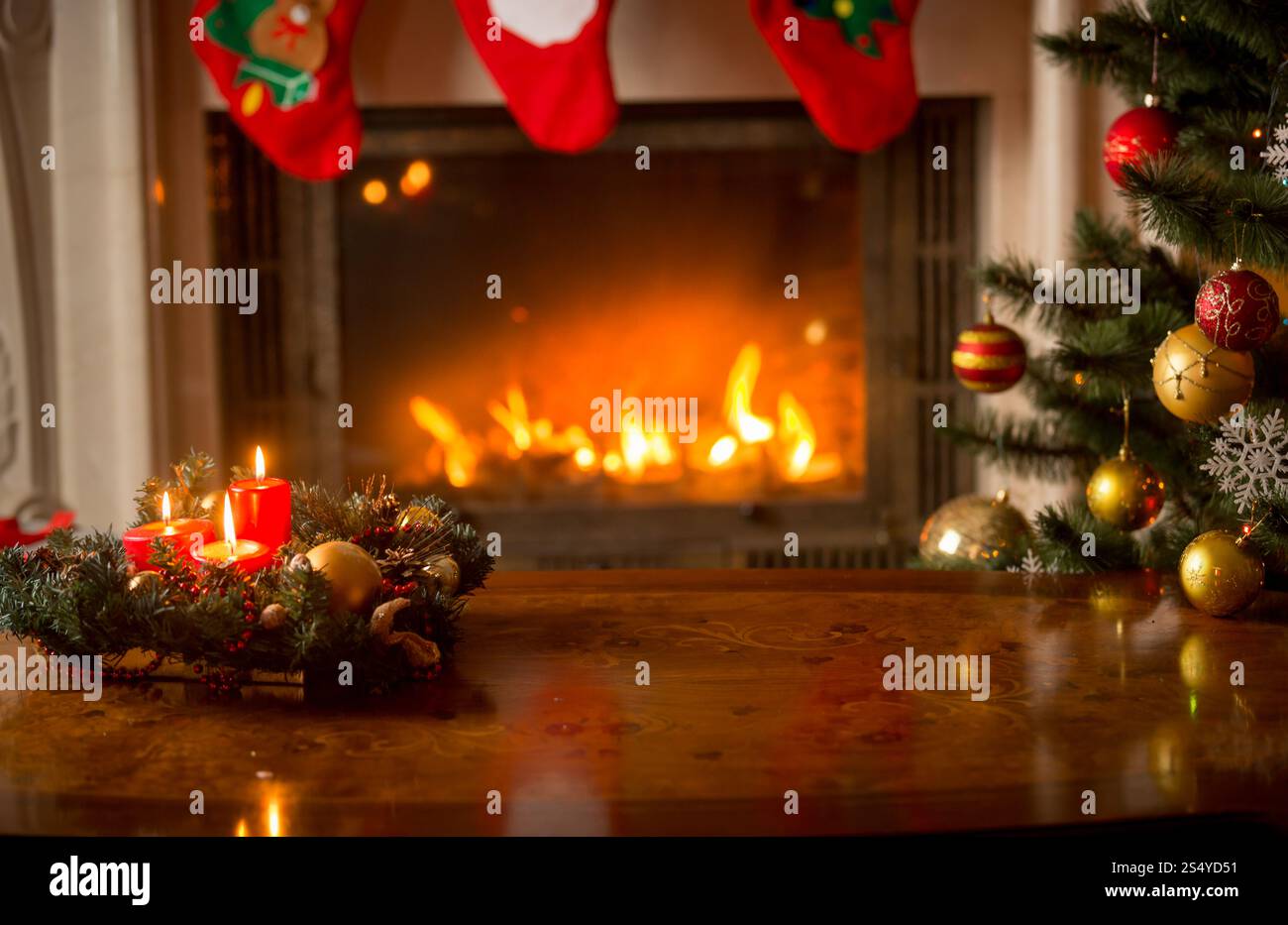 Weihnachtlicher Hintergrund mit brennenden Kerzen auf Holztisch vor Kamin und Weihnachtsbaum Stockfoto