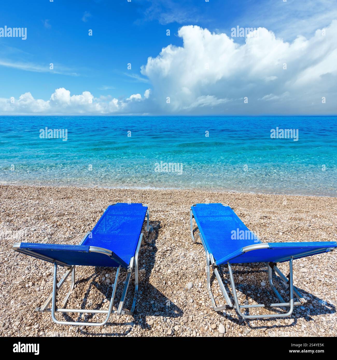 Sommer-morgen-Strand mit zwei Sonnenliegen und Wolken im Himmel (Albanien). Zwei Schüsse feststeppen Bild. Stockfoto