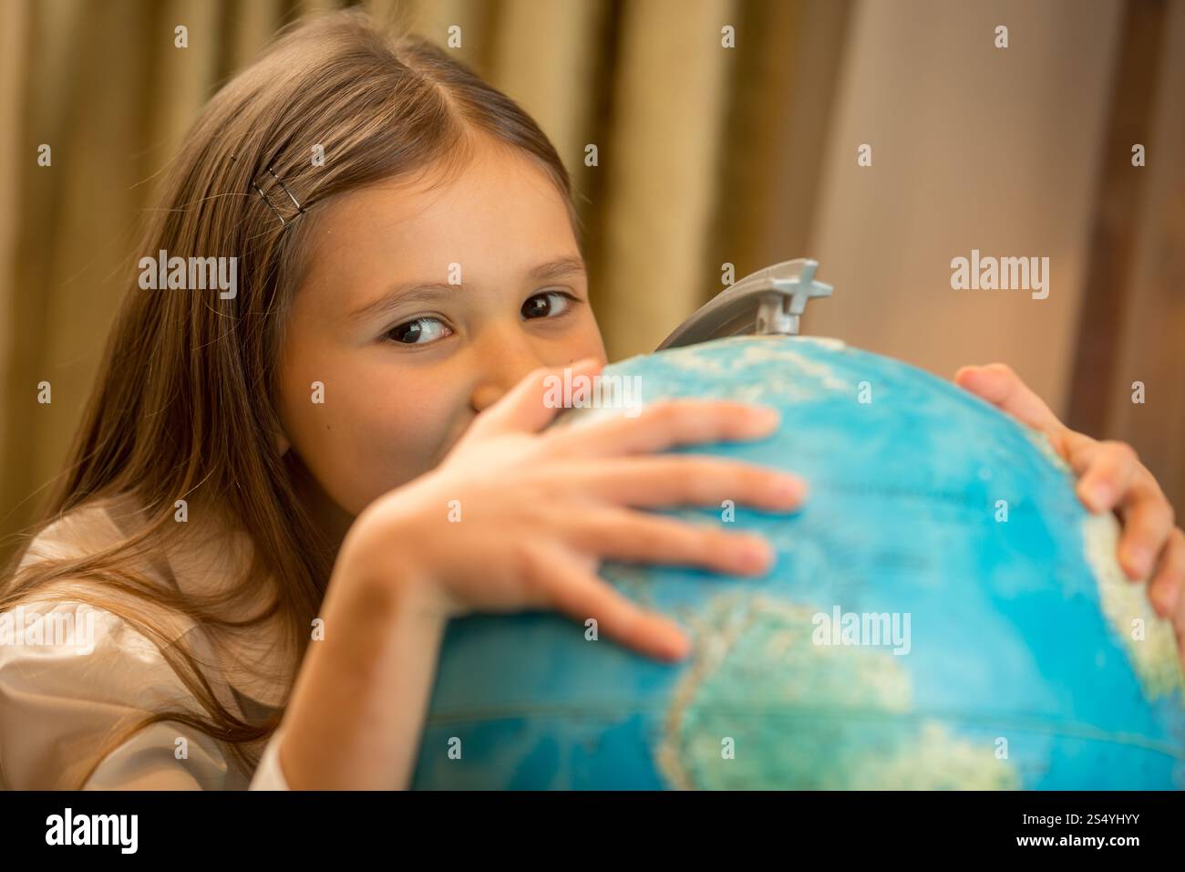Porträt eines niedlichen Mädchens, das Hand auf der Erdkugel hält Stockfoto