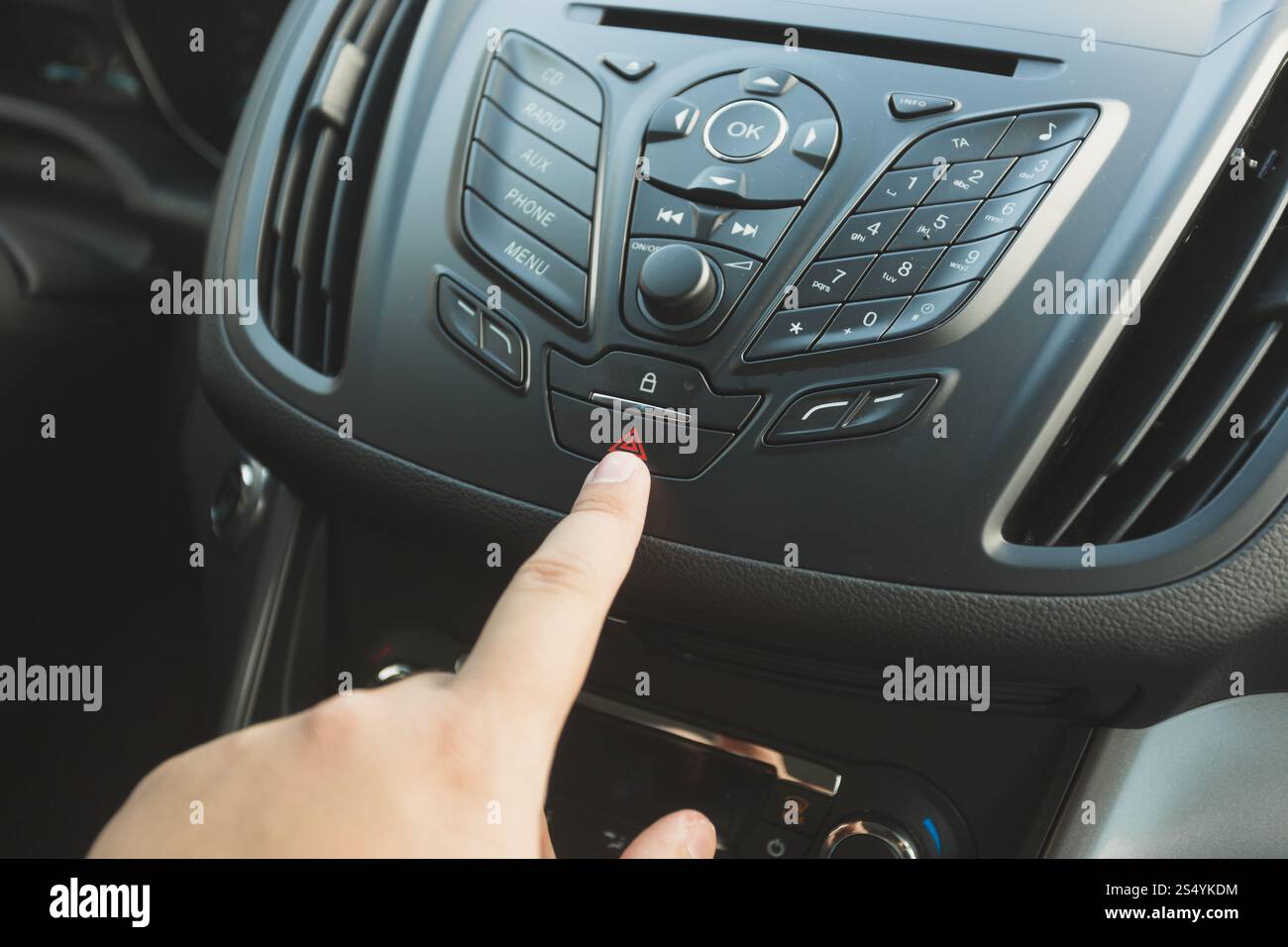 Nahaufnahme des Fahrers, der die Notruftaste auf dem Armaturenbrett des Fahrzeugs drückt Stockfoto