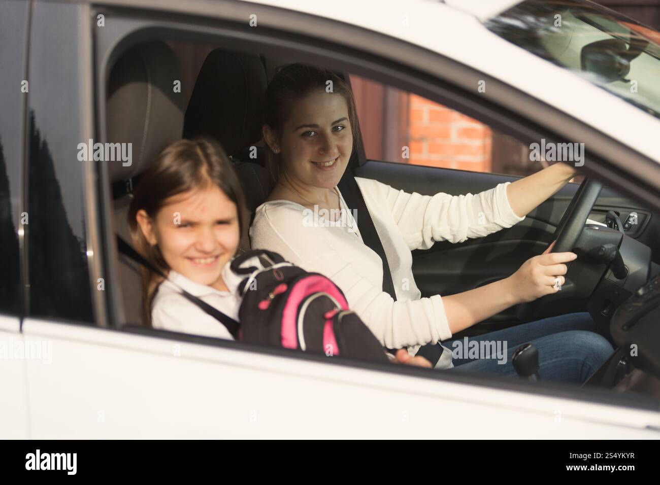 Schöne Mutter, die mit Tochter Auto zur Schule fährt Stockfoto