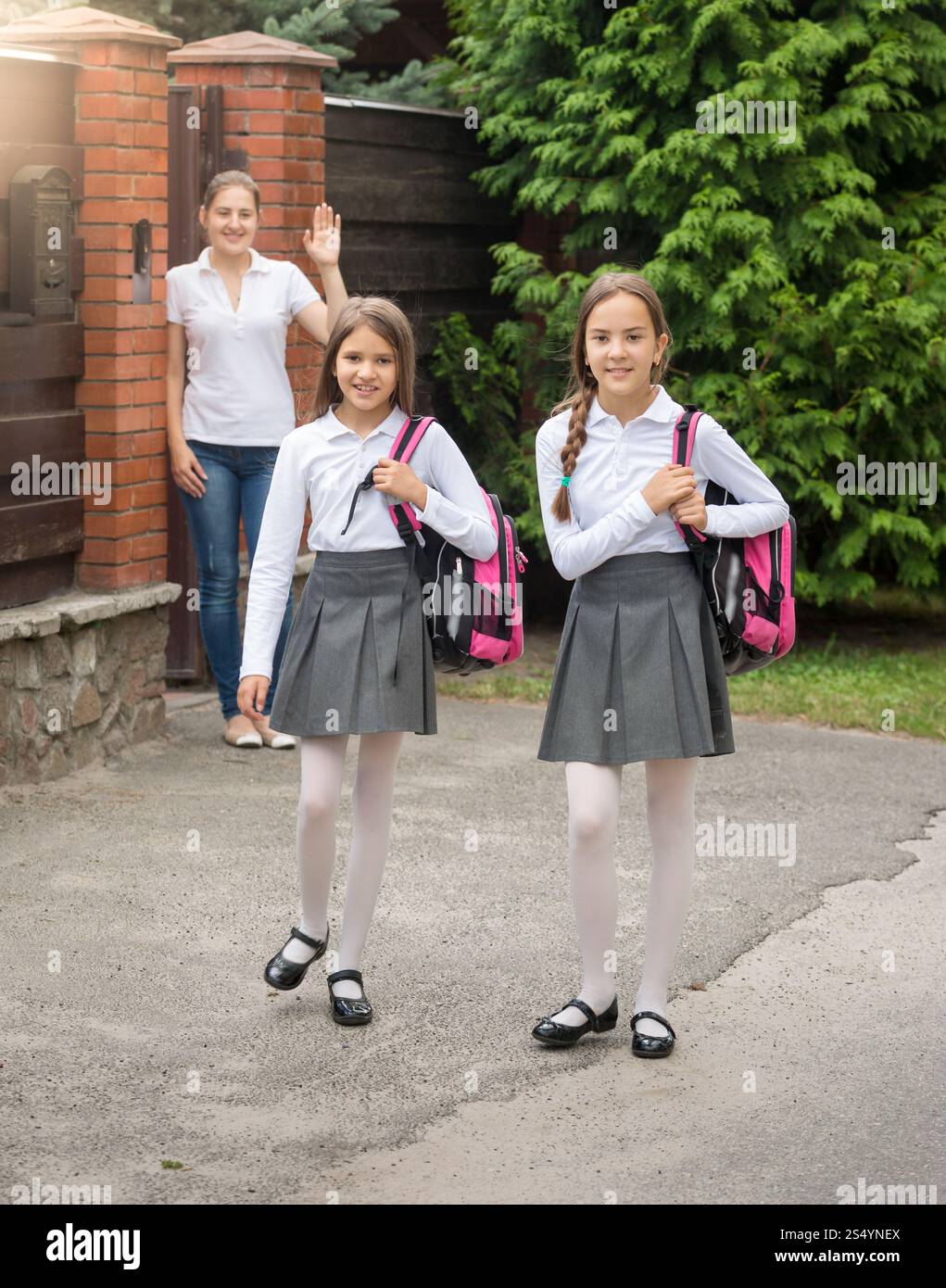 Zwei süße lächelnde Mädchen mit Taschen, die morgens zur Schule gehen Stockfoto