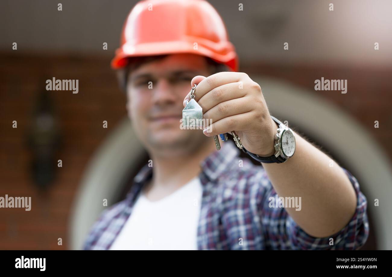 Bauarbeiter hält Schlüssel aus dem neuen Haus in der Hand Stockfoto