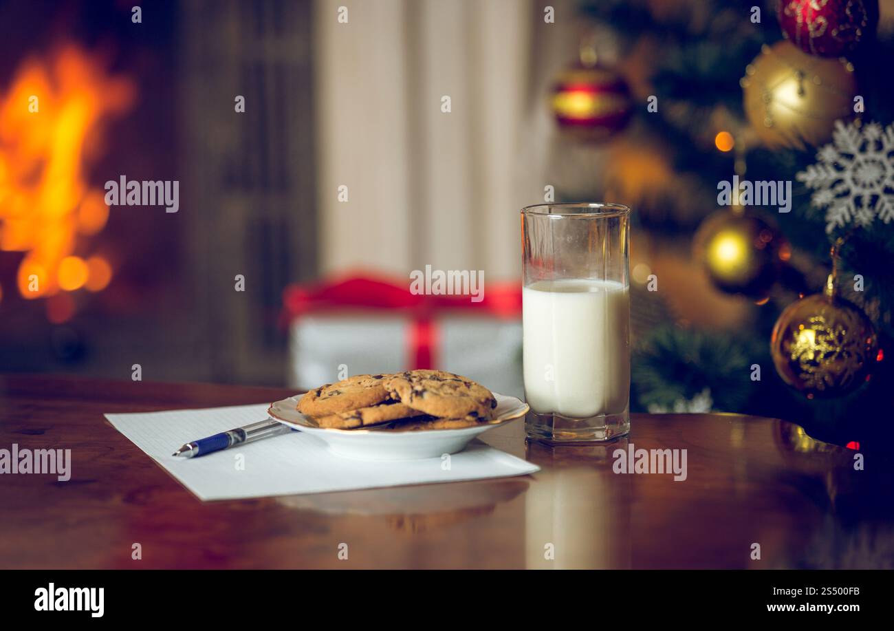 Nahaufnahme von Leckereien und Brief an den Weihnachtsmann auf Holztisch neben dem Weihnachtsbaum Stockfoto