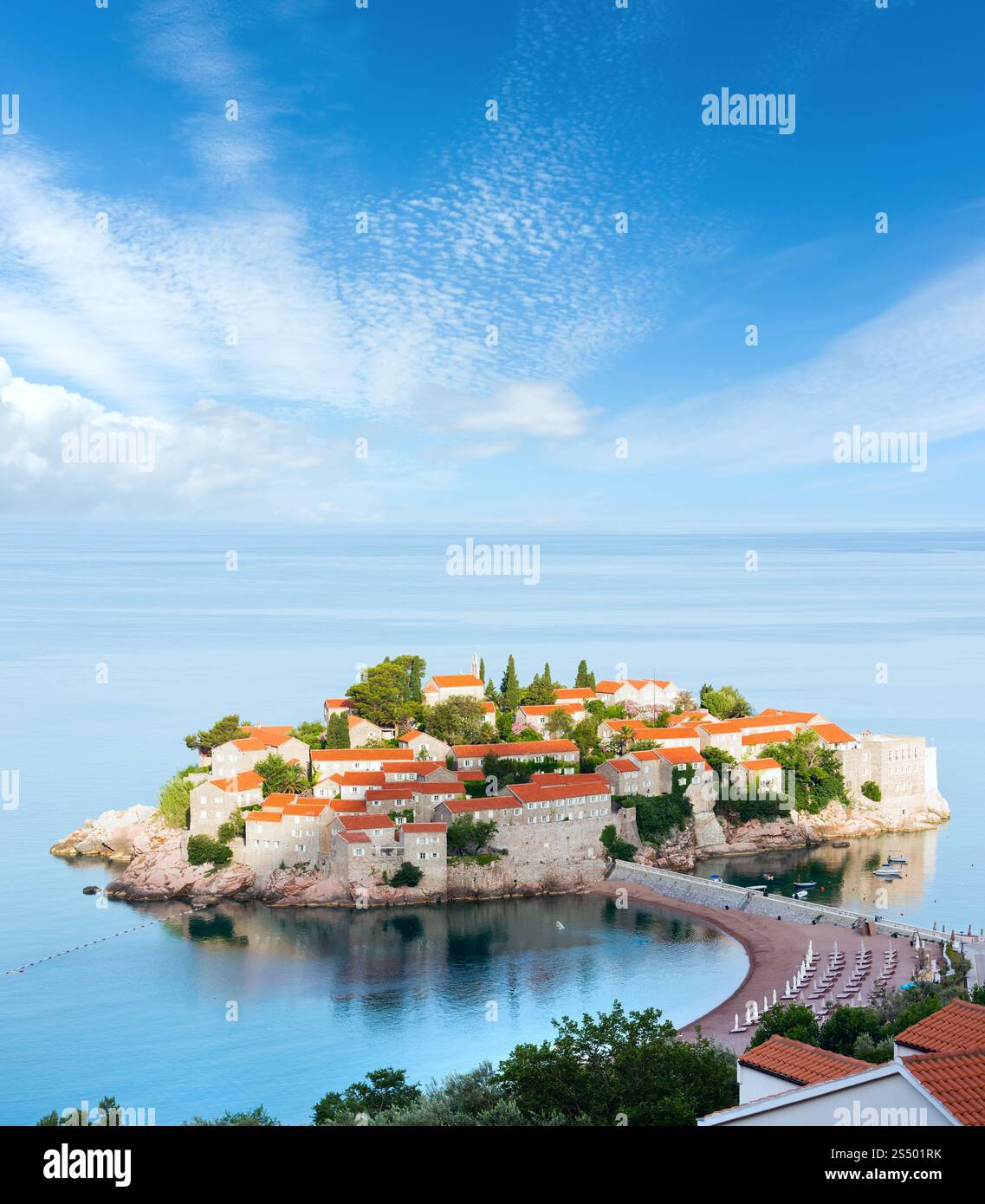 Der morgendliche Blick auf die Sveti Stefan Insel mit Strand und Stadt - Hotel (Montenegro, in der Nähe von Budva) und blauem, malerischem Himmel darüber. Vier Schüsse Stich Stockfoto