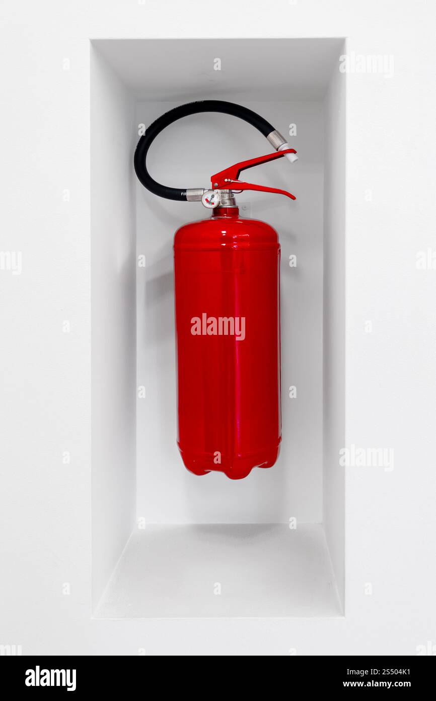 Roter Feuerlöscher hängt in einer Nische an der weißen Wand zur ersten Hilfe Stockfoto
