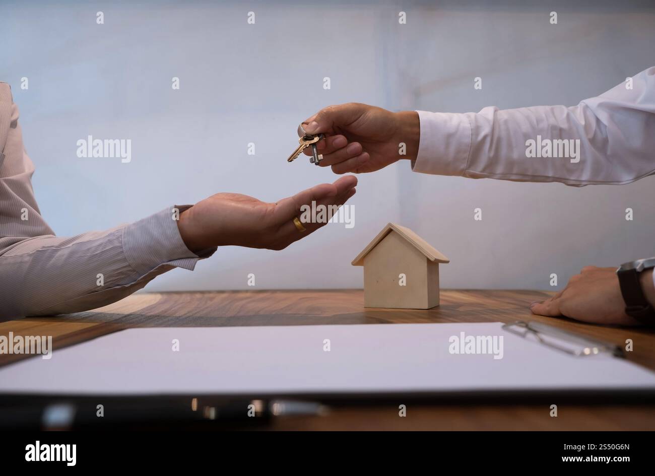 Immobilienmakler, der dem Kunden nach Vertragsunterzeichnung Schlüssel gibt Stockfoto