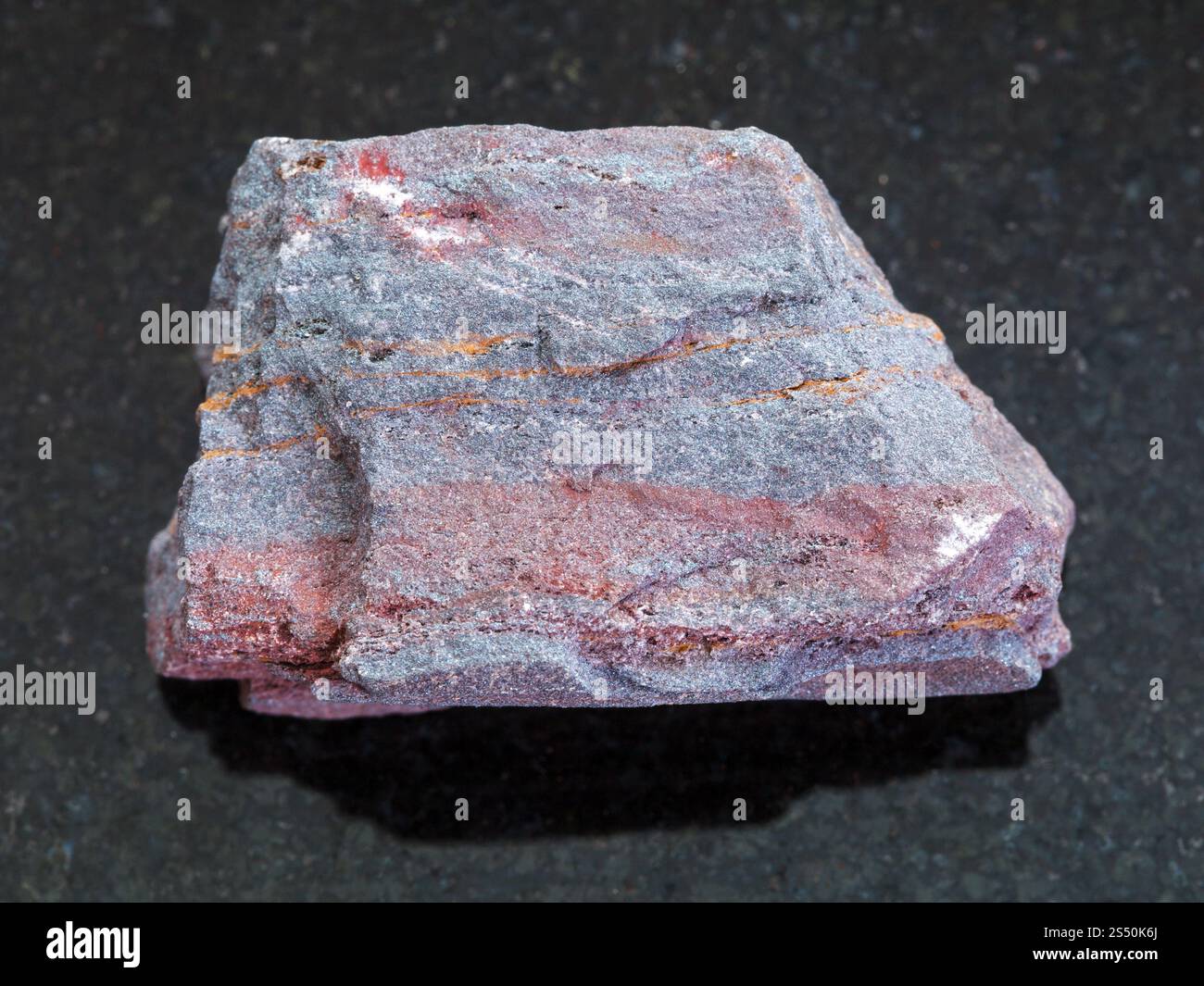 Makroaufnahmen von natürlichen Mineralgestein Muster - Grobe jaspilite (eisenhaltiges Quarzit) Stein auf dunklem Granit Hintergrund Stockfoto