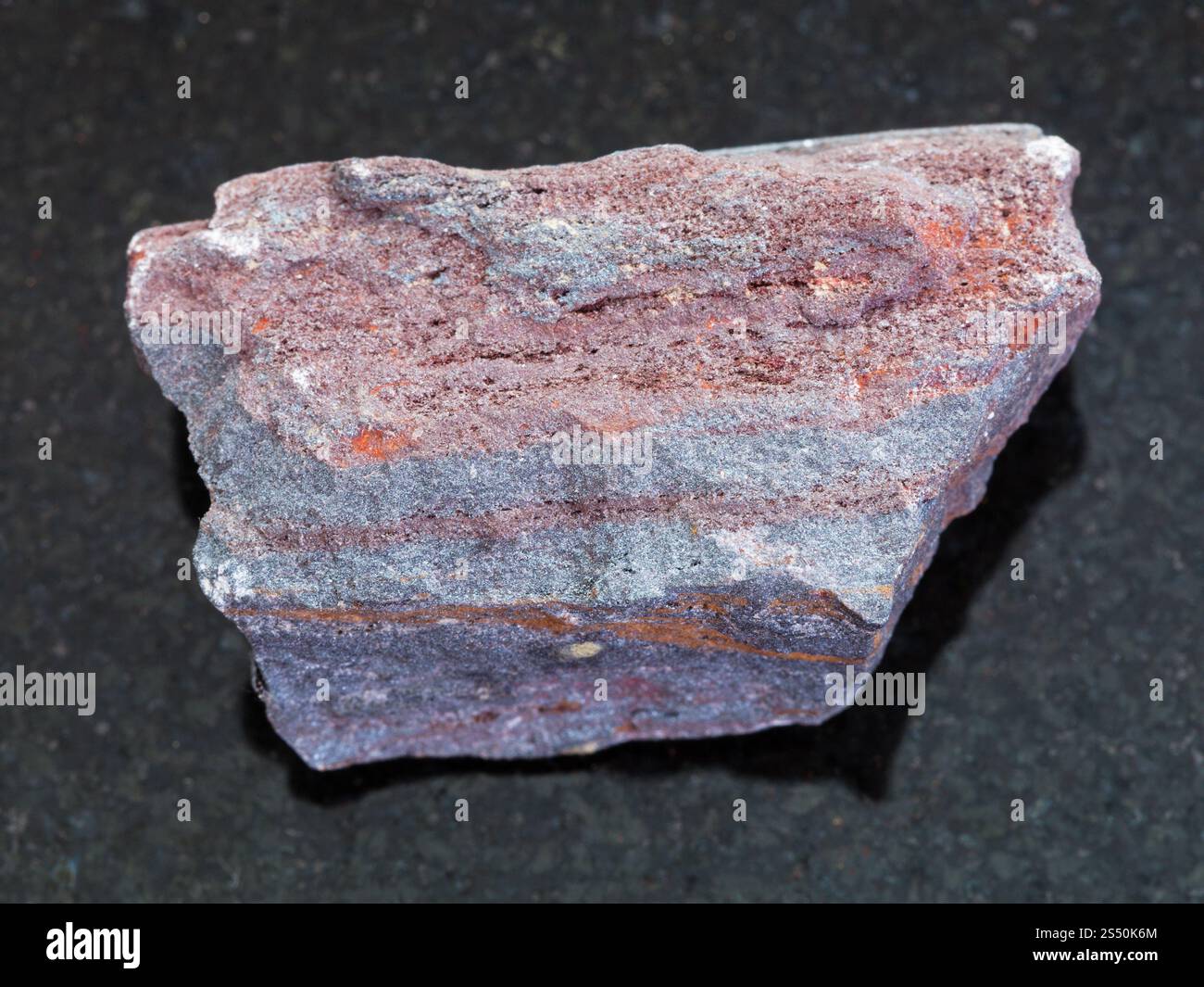Makroaufnahmen von natürlichen Mineralgestein Muster - raw jaspilite (eisenhaltiges Quarzit) Stein auf dunklem Granit Hintergrund Stockfoto